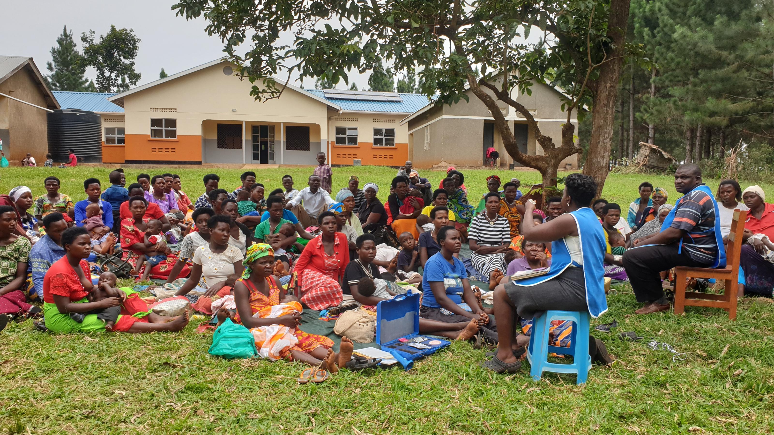 Unter einem Baum in einem ugandischen Dorf haben sich rund 50 Frauen versammelt, sie sitzen im Gras. Eine medizinische Angestellte stellt ihnen die verschiedenen Verhütungsmittel vor.