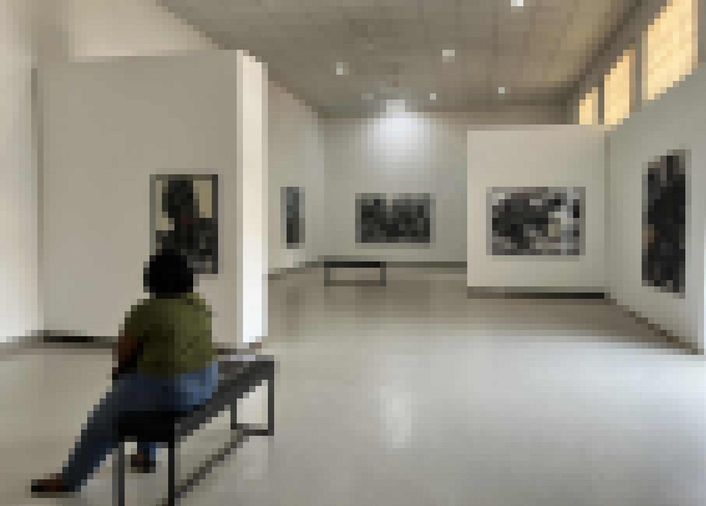 Eine Frau sitzt auf einer Bank im Ausstellungsraum der Galerie. An den Wänden hängen großformatige Bilder in schwarz-weiß.