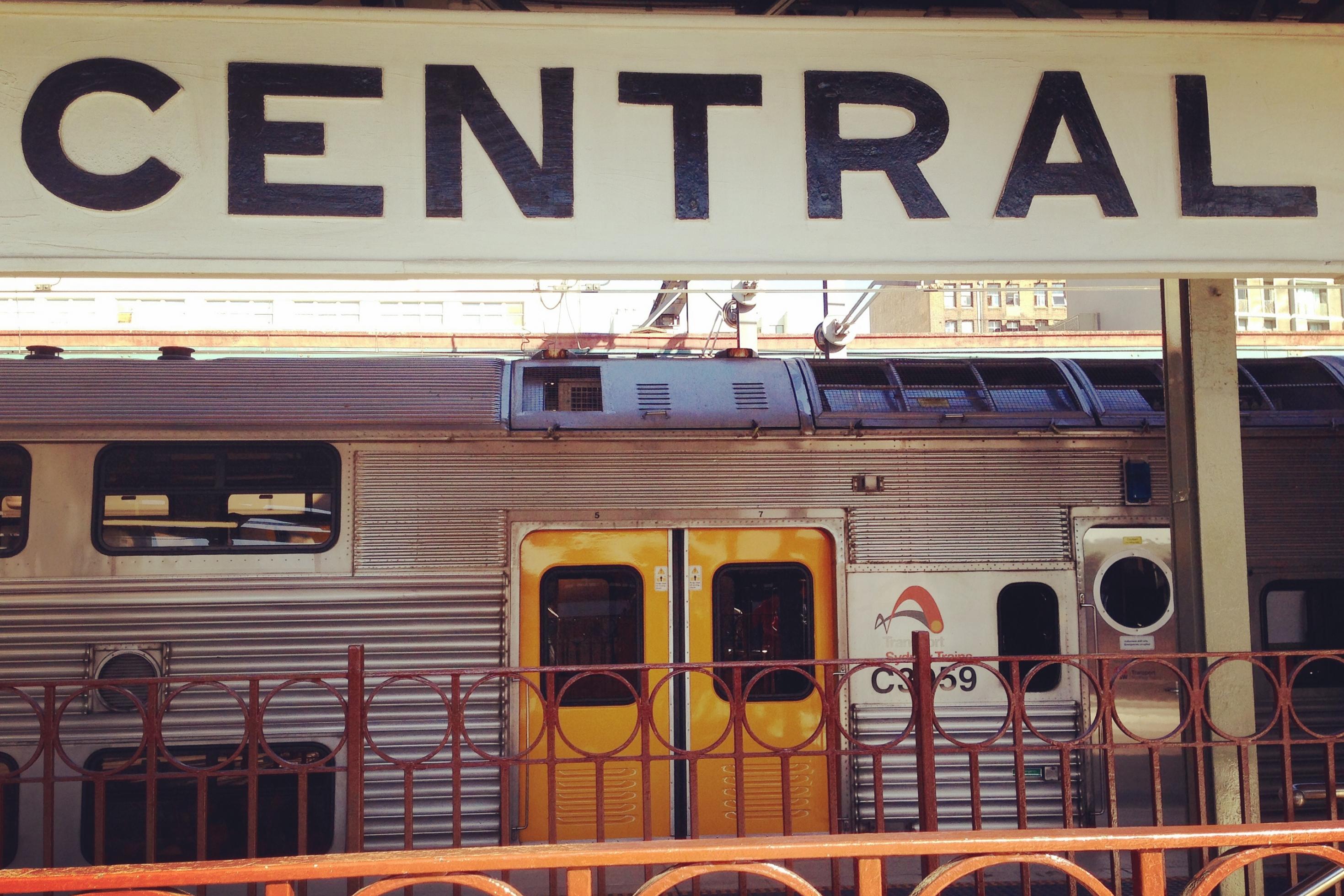 Ein Schild mit der Aufschrift „Central“ auf dem Hauptbahnhof von Sydney, im Hintergrund ein innerstädtischer Doppeldeckerzug.