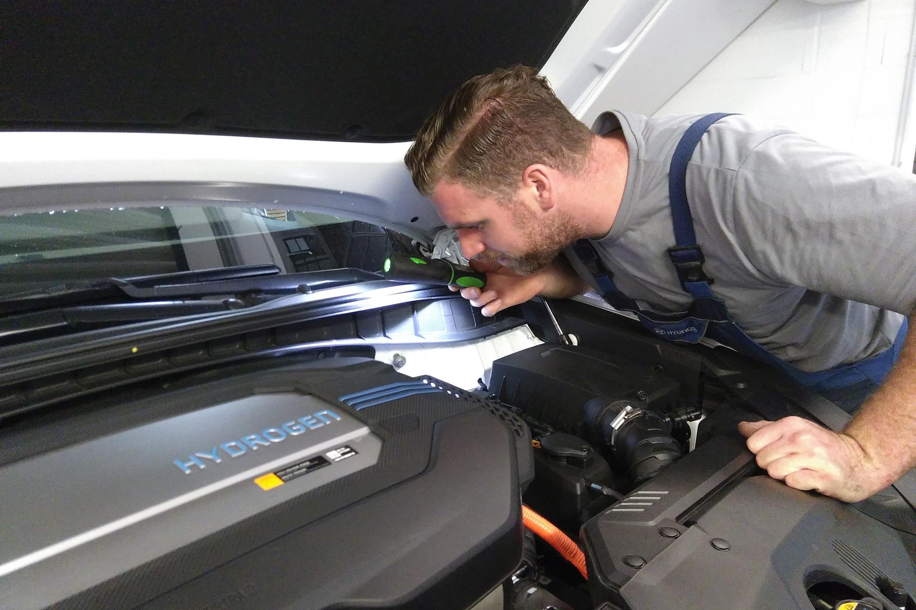 Ein Mechaniker leuchtet in den Motorraum des Hyundai Nexo