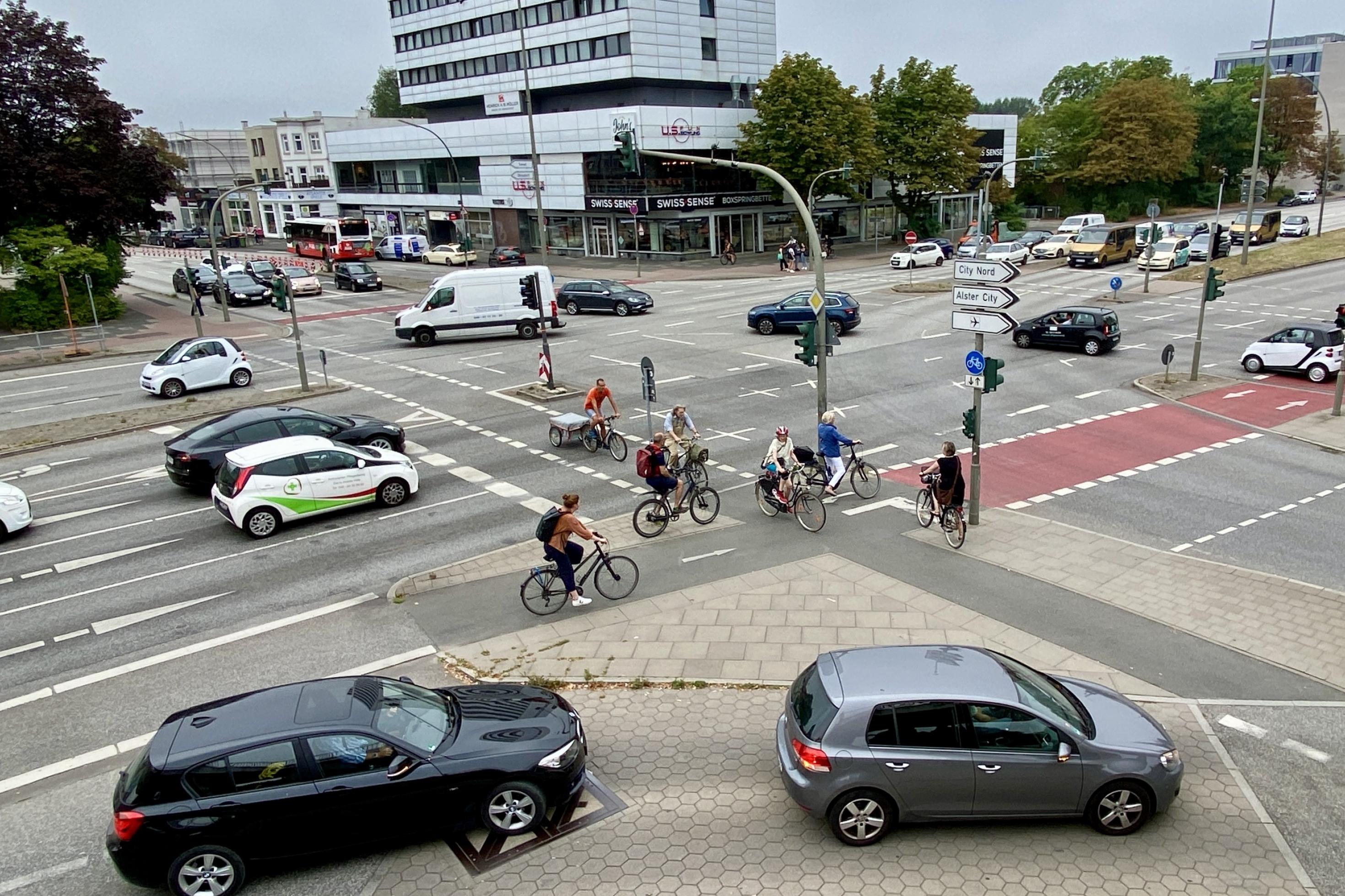 Ein Blick auf eine Kreuzung aus der Vogelperspektive, Radfahrer und Autos passieren die Kreuzung