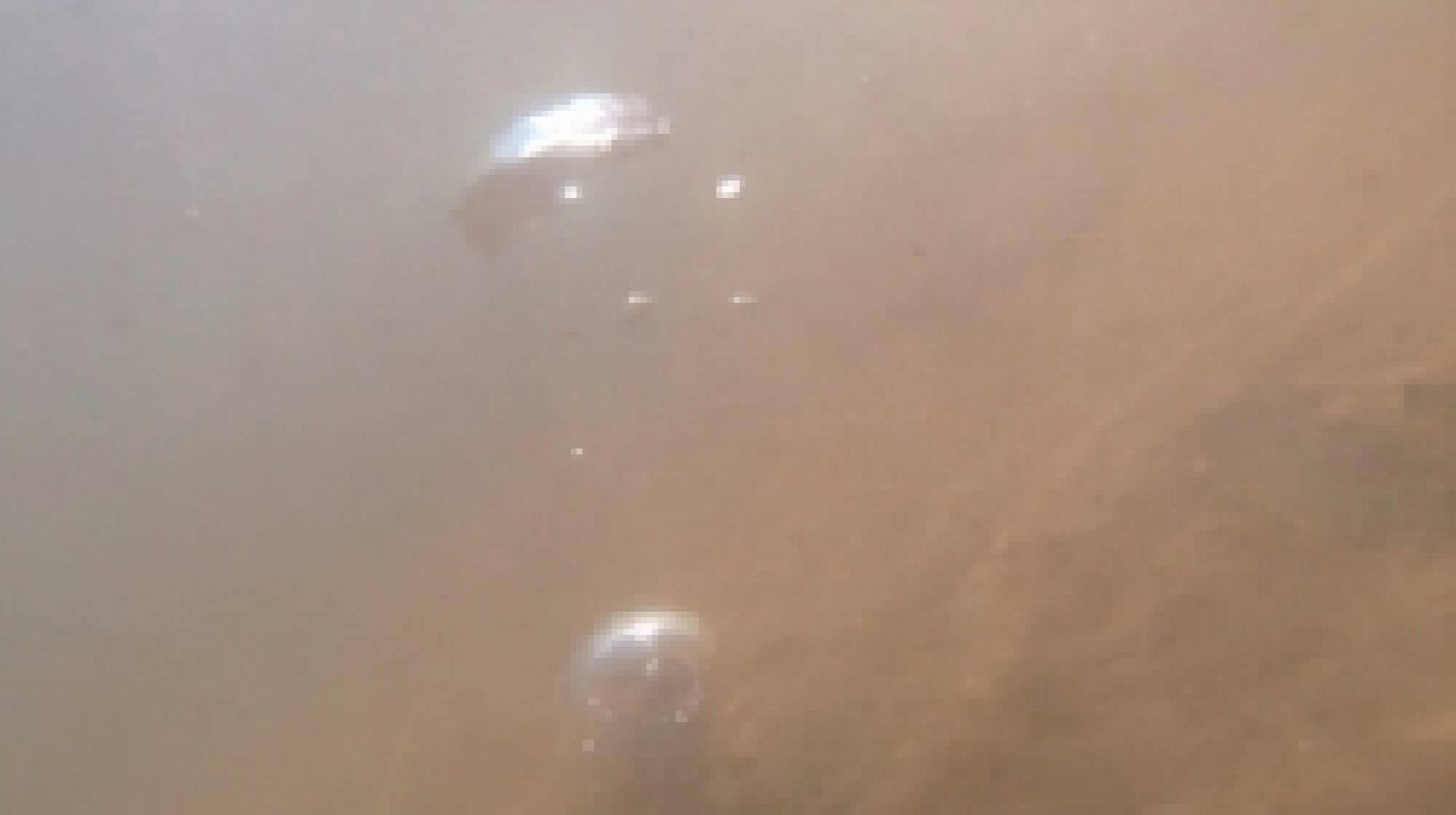 Silbern schimmernde Gasblasen  unter Wasser vor dem Hintergrund eines rötlich-braunes Sediments in einem Bach.