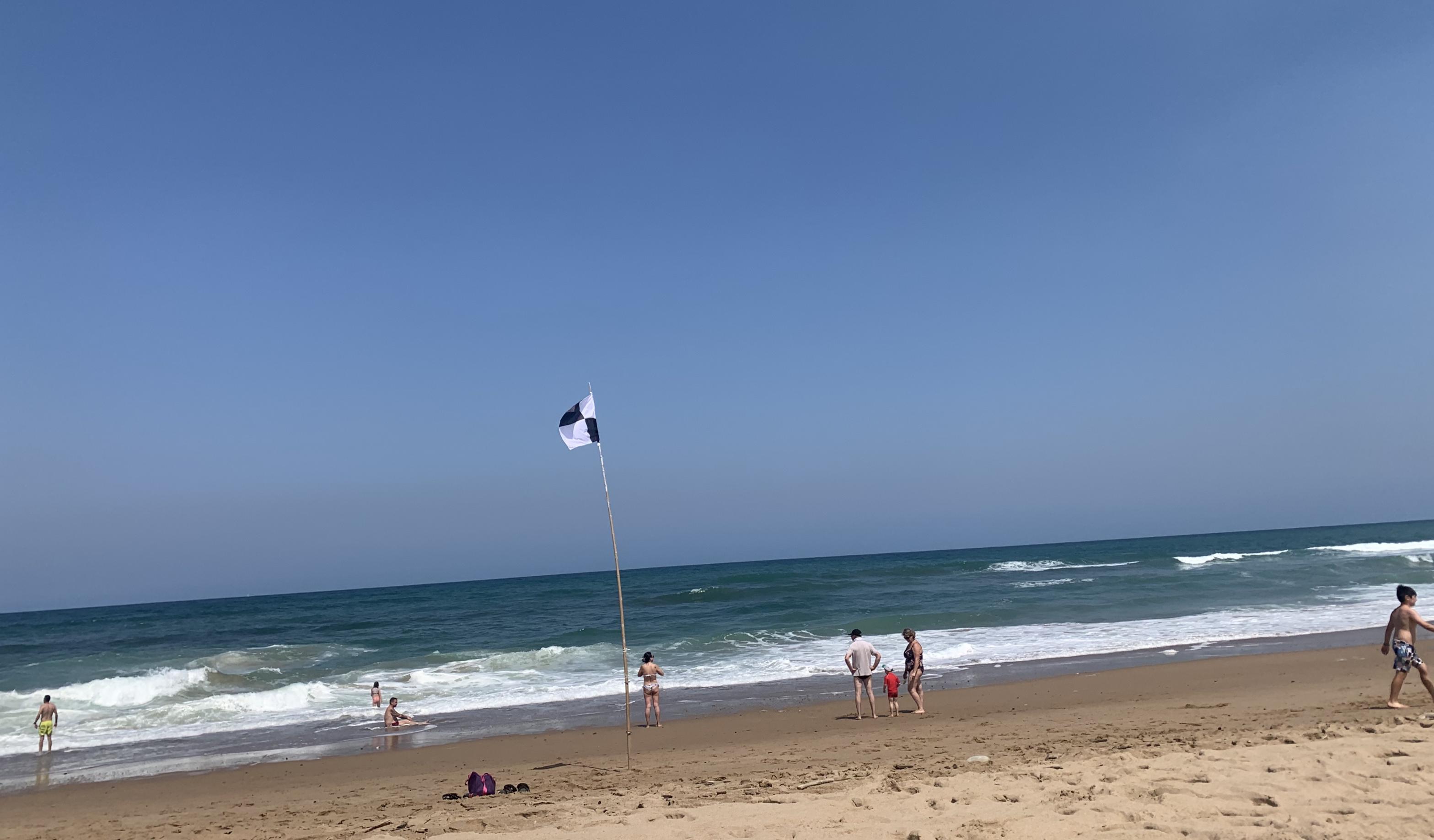 Bild zeigt Strand mit Flagge an der französischen Atlantikküste, die die Badezone eingrenzt.