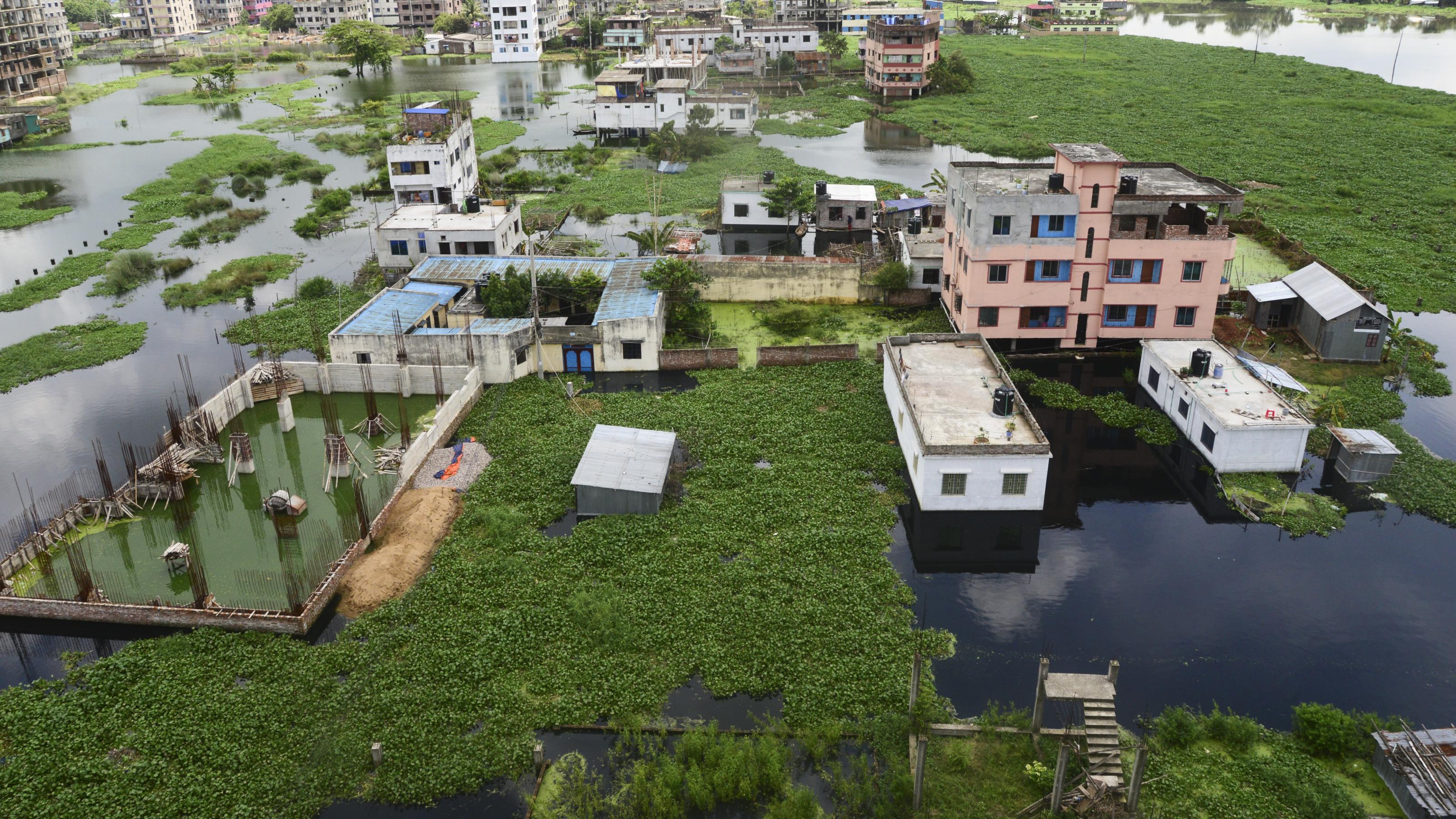 Häuser in Dhaka, Bangladesch, umgeben von grauem Wasser
