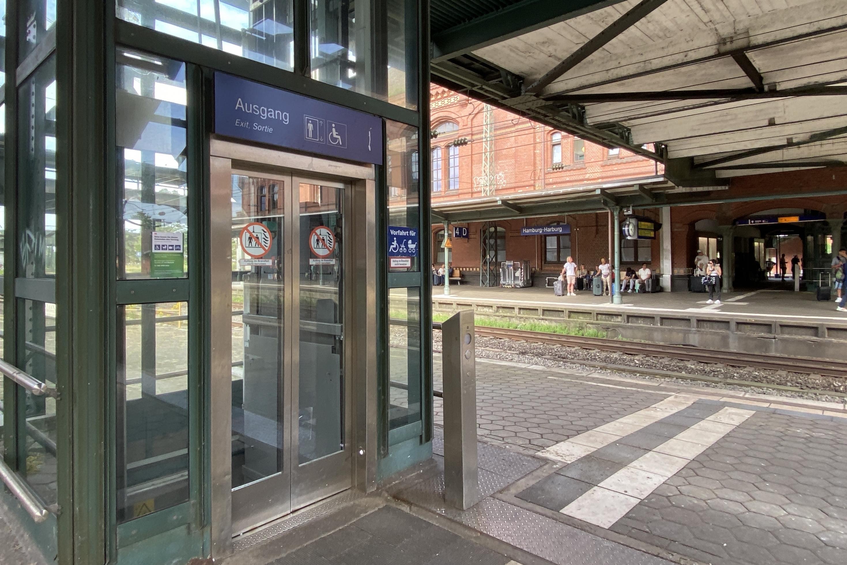 Ein leerer Fahrstuhl auf dem Gleis eines Bahnhofs. Im Hintergrund waren Menschen.