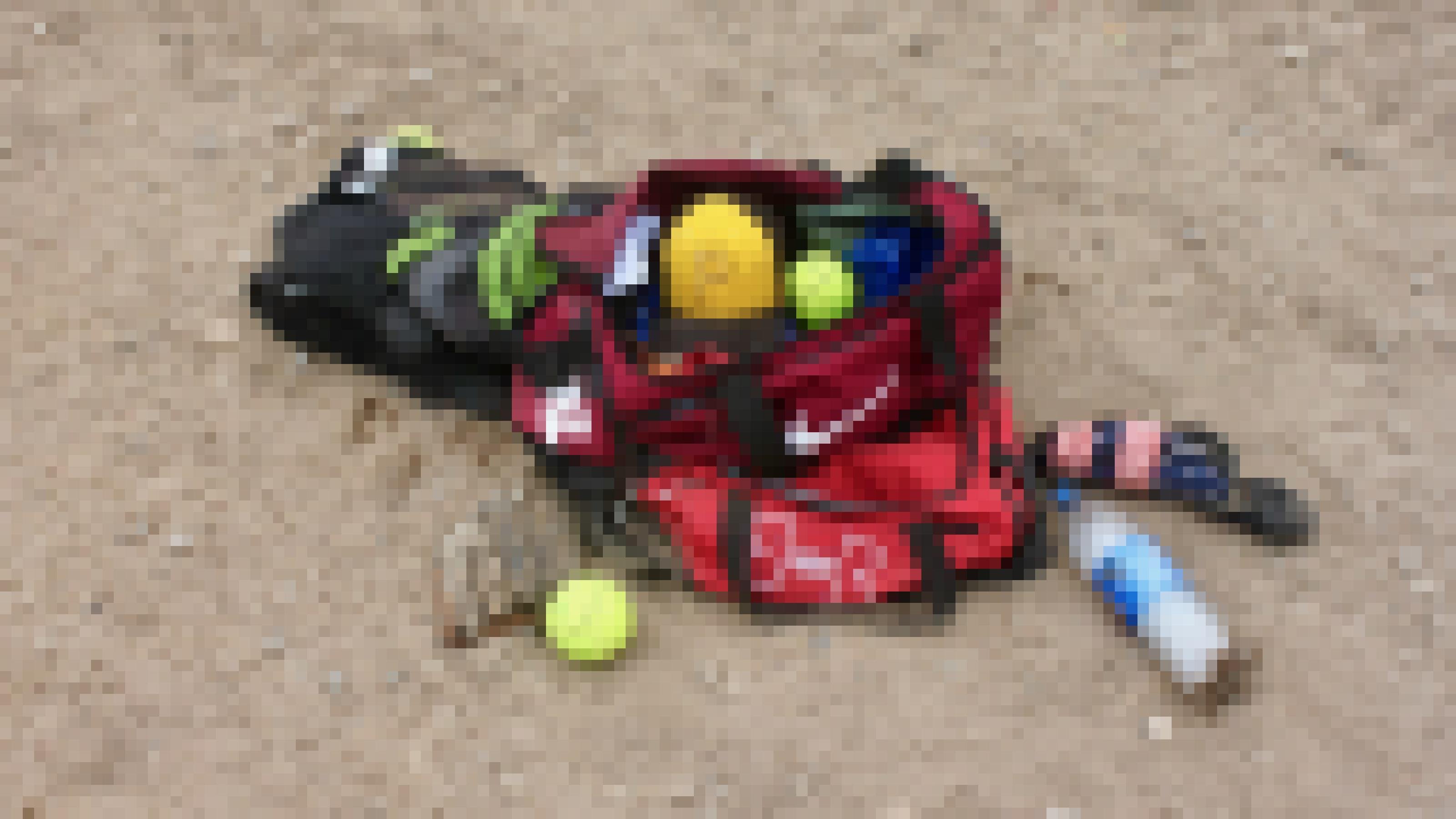Sporttasche auf sandigem Boden, mit offenem Reissverschluss. Darin ein Baseball-Cap, zwei grüne Bälle, daneben eine leere Wasserflasche.