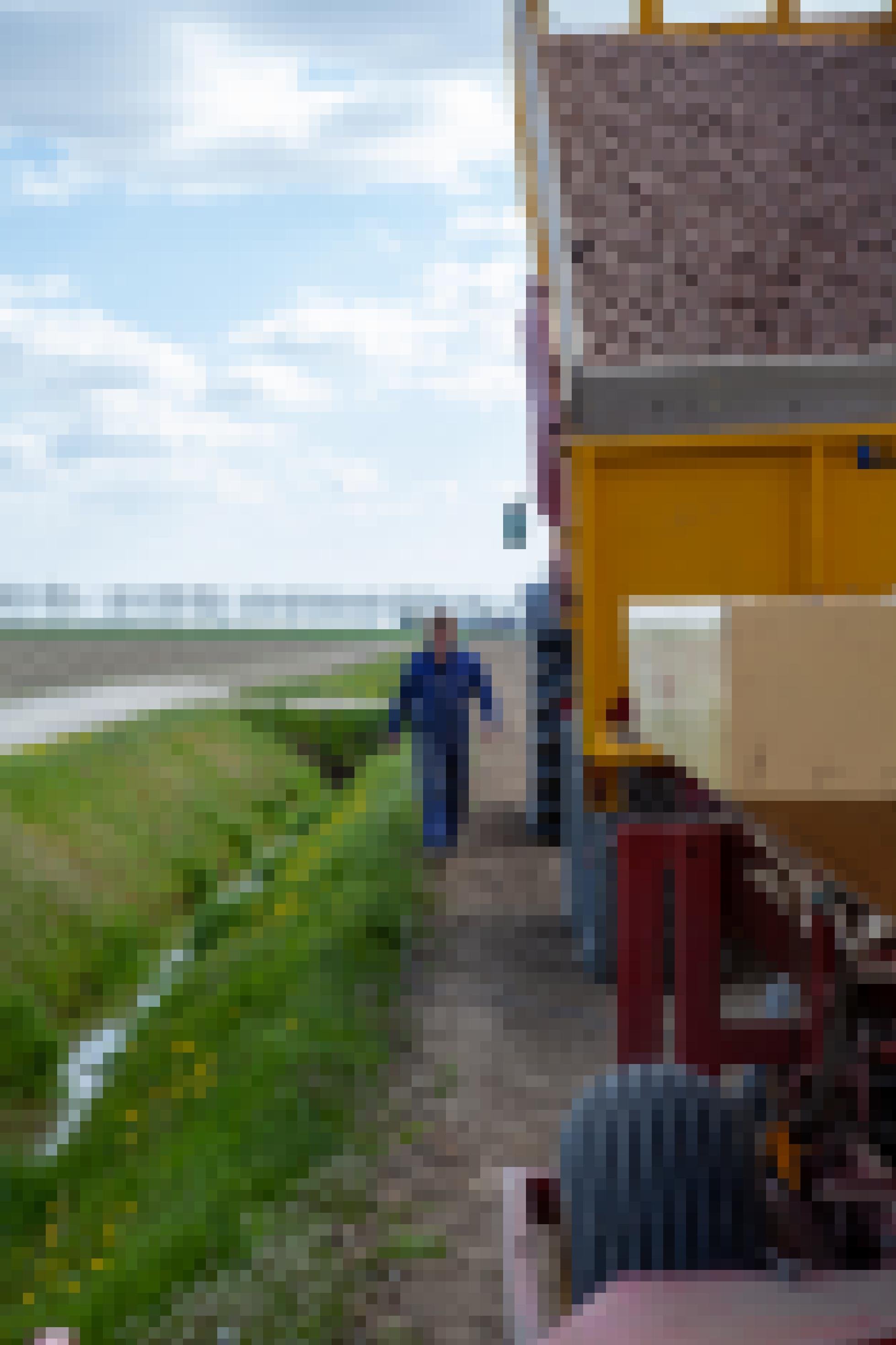 Ein Bauer in Blaumann geht neben einem Traktor her, der große Mengen Kartoffeln geladen hat.