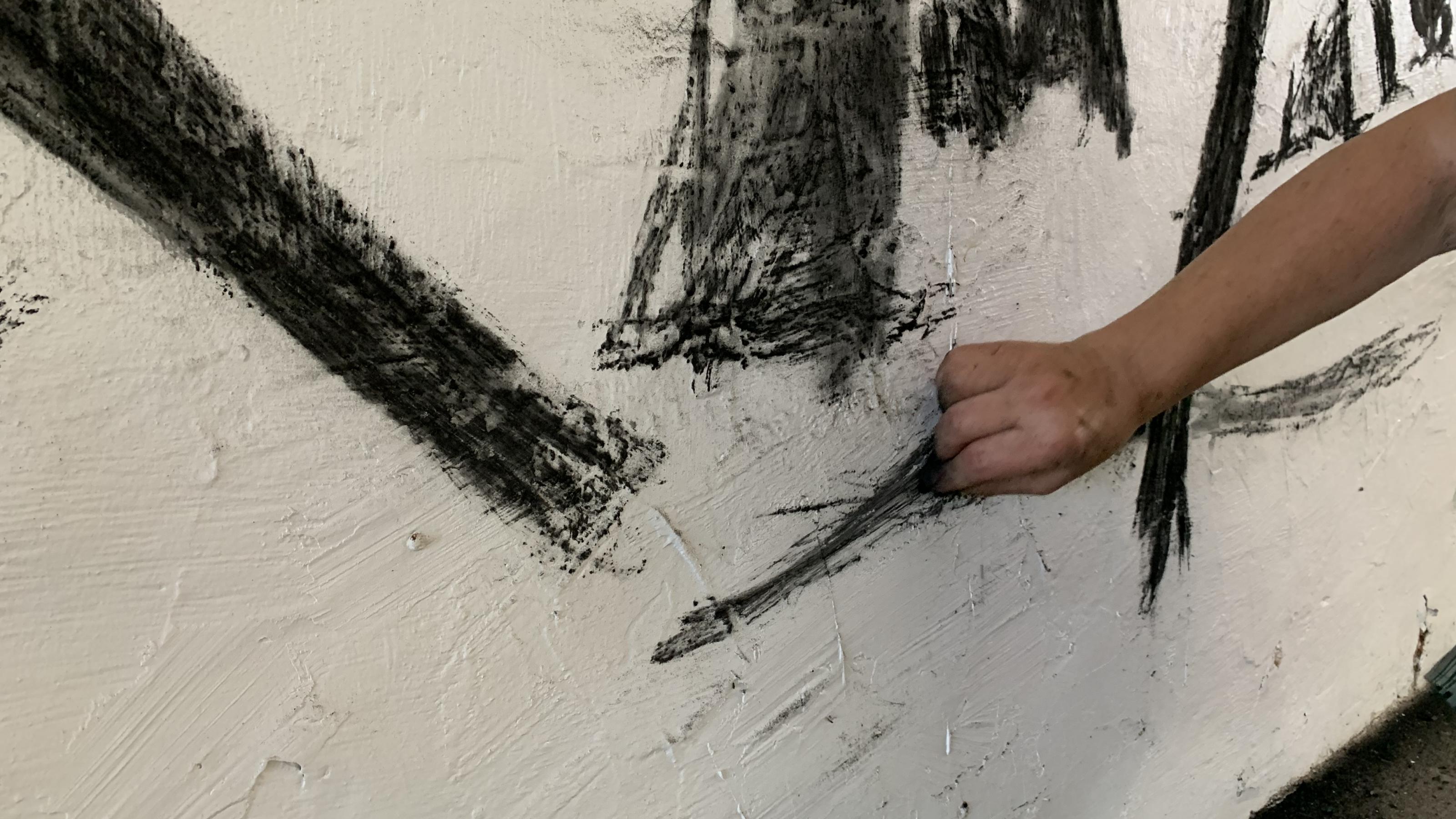 Man sieht die Hand von Belinda Broughton, wie sie mit Holzkohle malt.