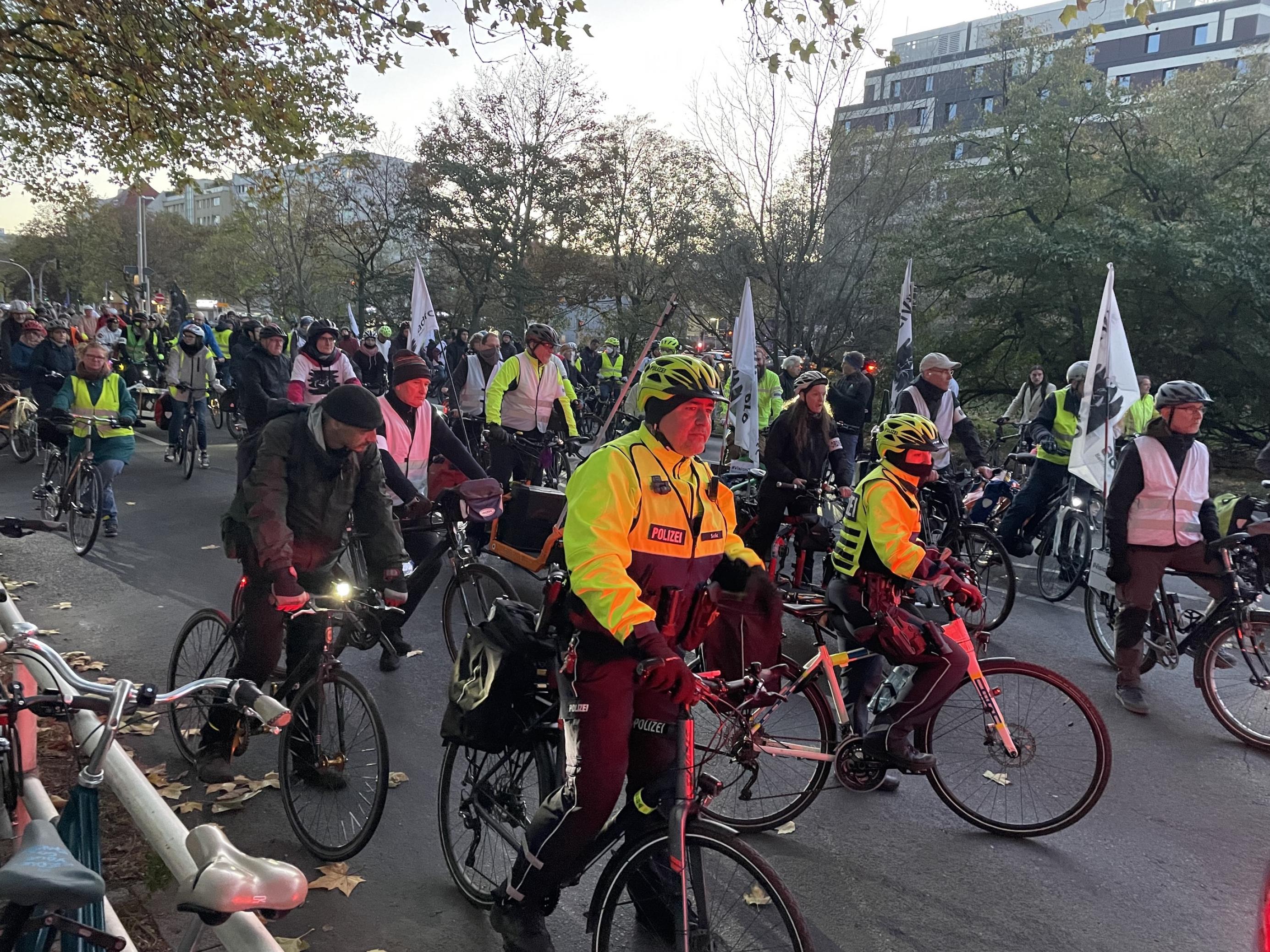 Radfahrende auf der Straße, angeführt von zwei Fahrradpolizisten.