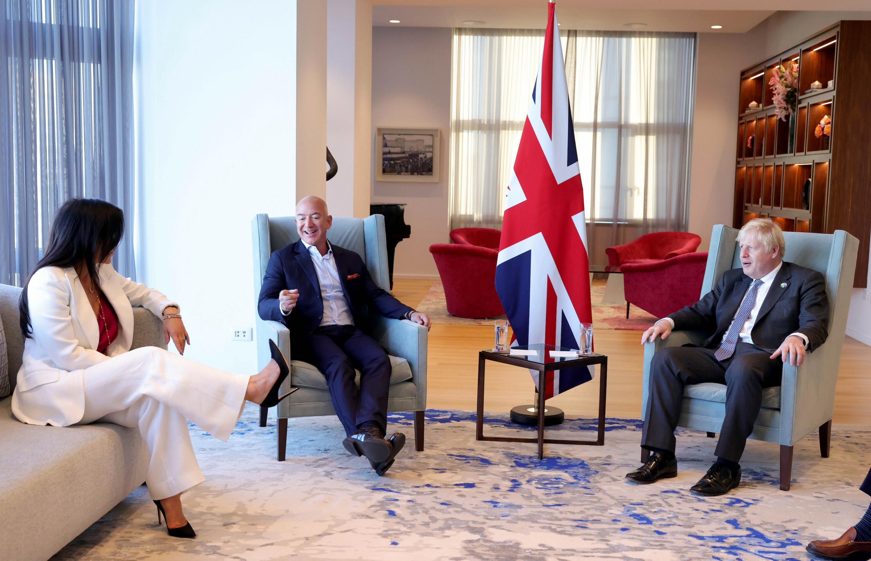 Bezos, Johnson und Sanchez in feinem Ambiente in New York, alle sitzen, im Zentrum eine britische Flagge.