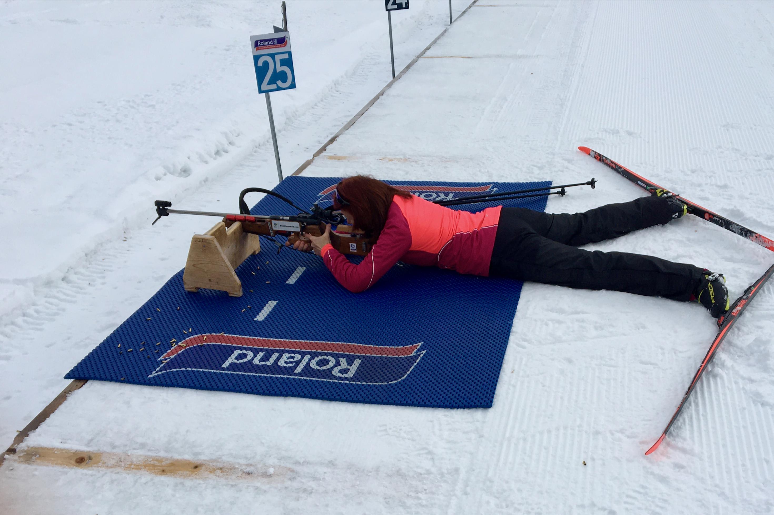 Biathlon, Frau liegt im Schnee und zielt