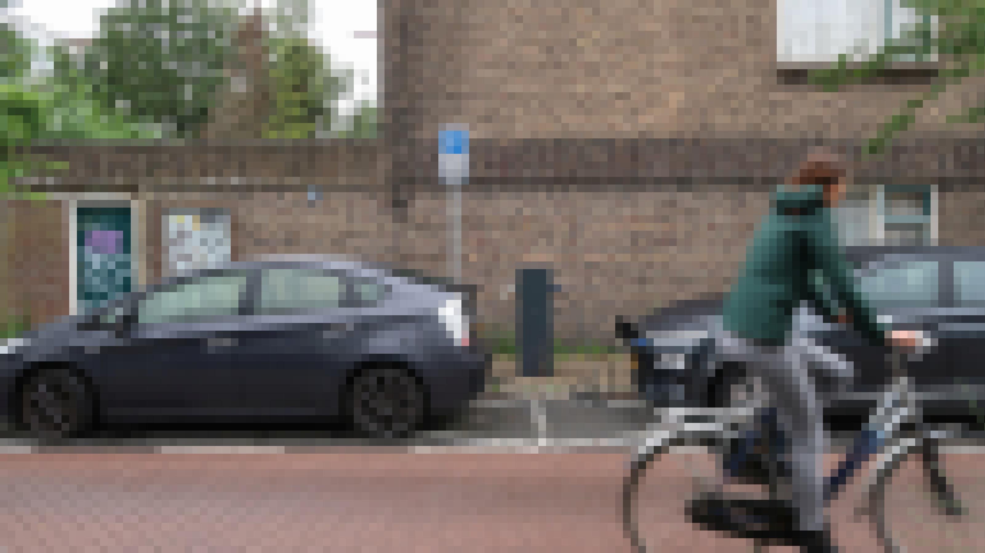 Eine Fahrradfahrerin fährt an zwei geparkten Elektroautos vorbei, die mit einer Ladestation verbunden sind.