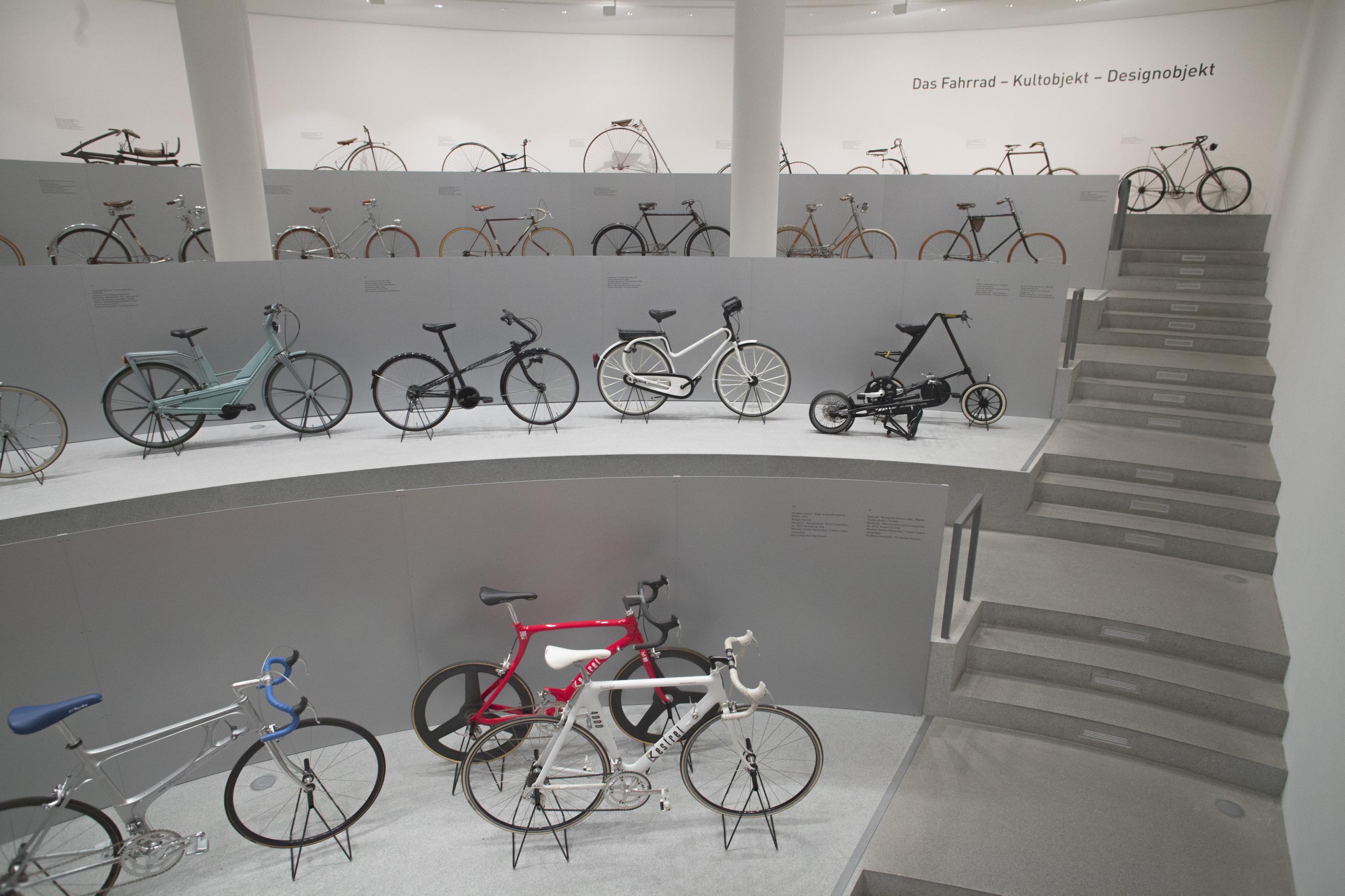 Blick ins Halbrund der Ausstellung  „Das Fahrrad – Kultobjekt – Designobjekt“ mit etlichen Vehikeln.