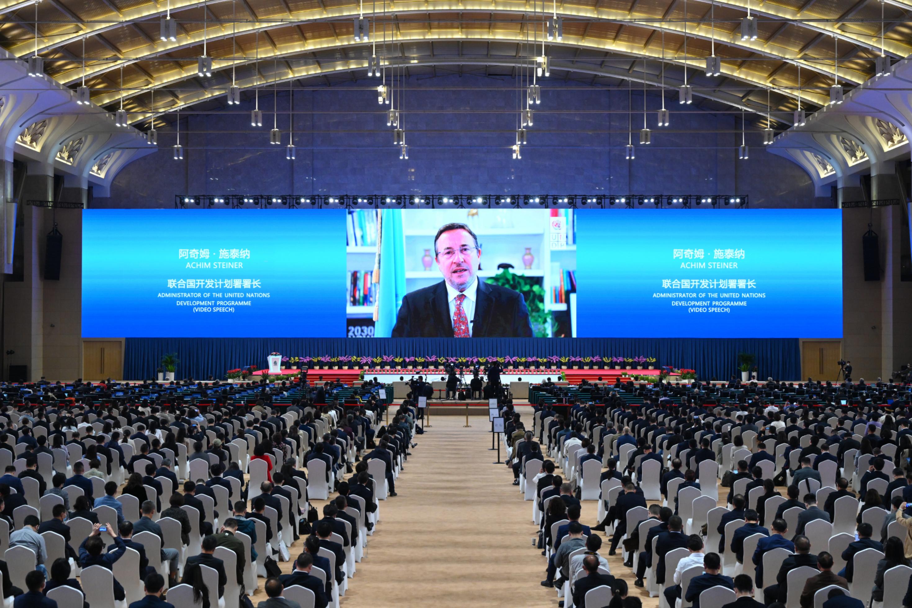 Blick in den riesigen Konferenzsaal und die Leinwand, auf der die Videobotschaft von UNDP-Chef Achim Steiner zu sehen ist.