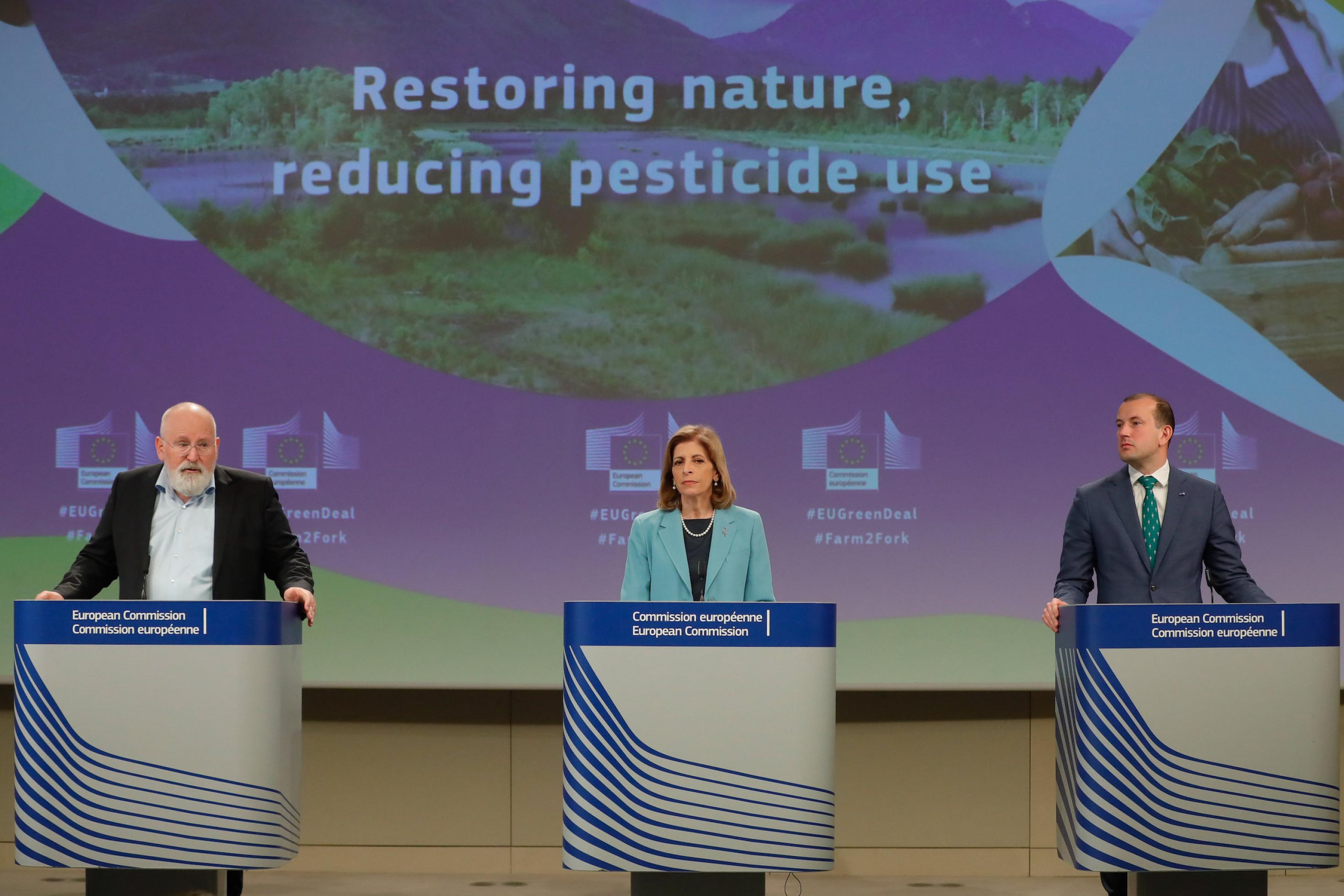 Die drei stehen an Pulten vor einer Wand mit der Aufschrift Restoring nature, reducing pesticide use.
