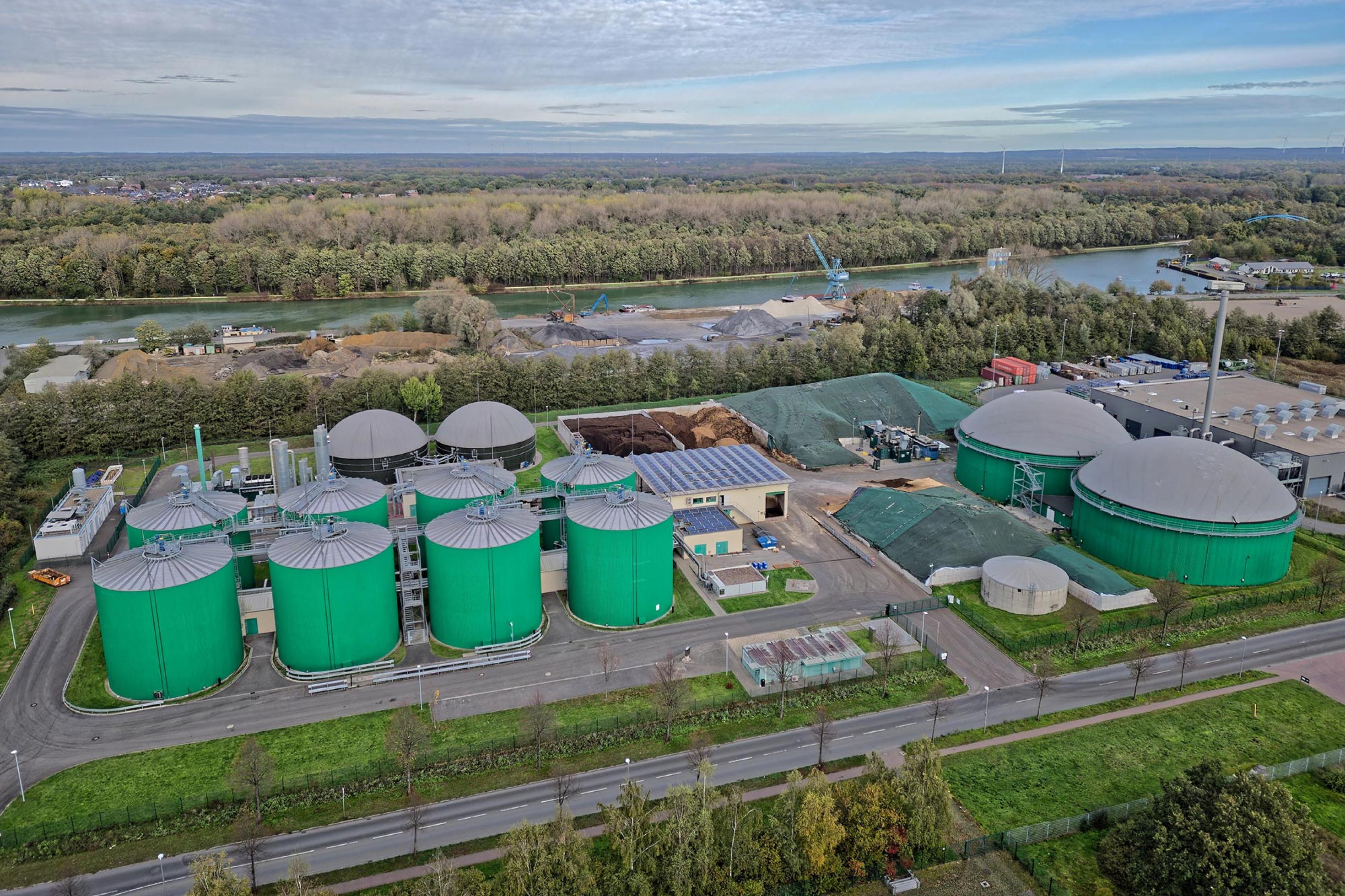 Vogelperspektive auf einen Anlagenpark mit runden Silos mit grünen Wänden und grauen Dächern.