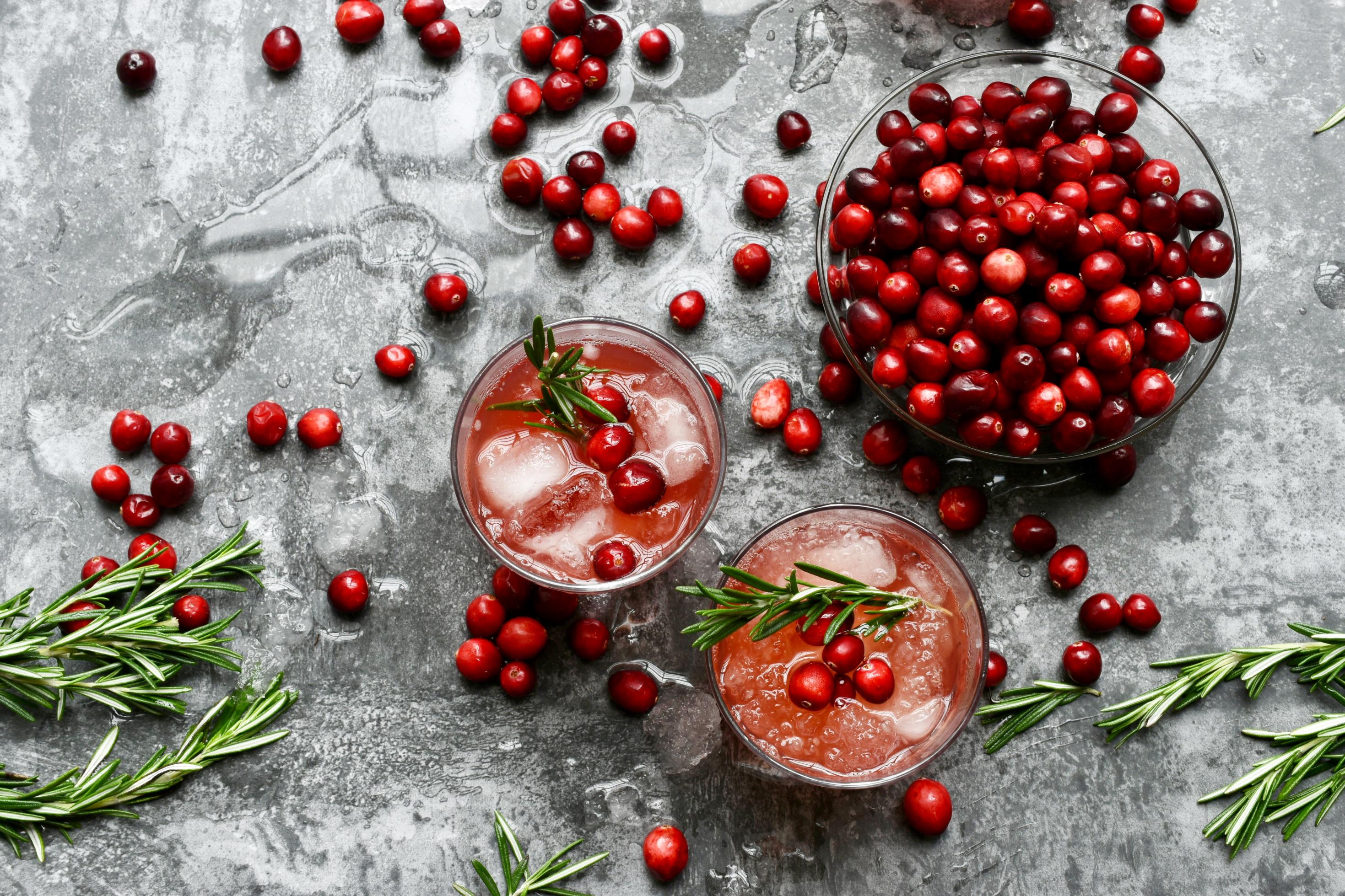 ranberrys in einer Glasschale und in Cocktails mit Rosmarin