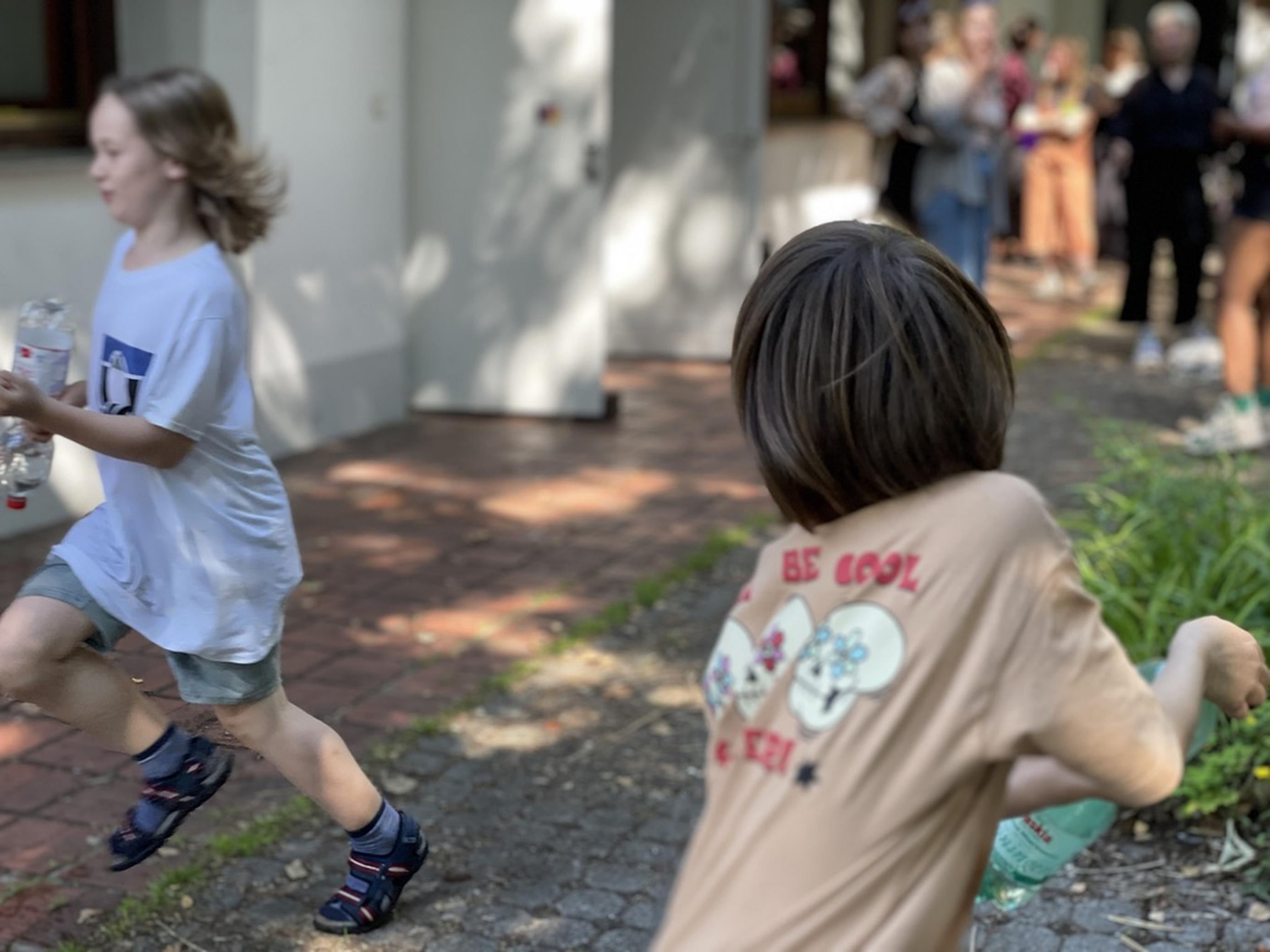 Zwei Jungen rennen auf einem Hof in einem Spiel miteinander.