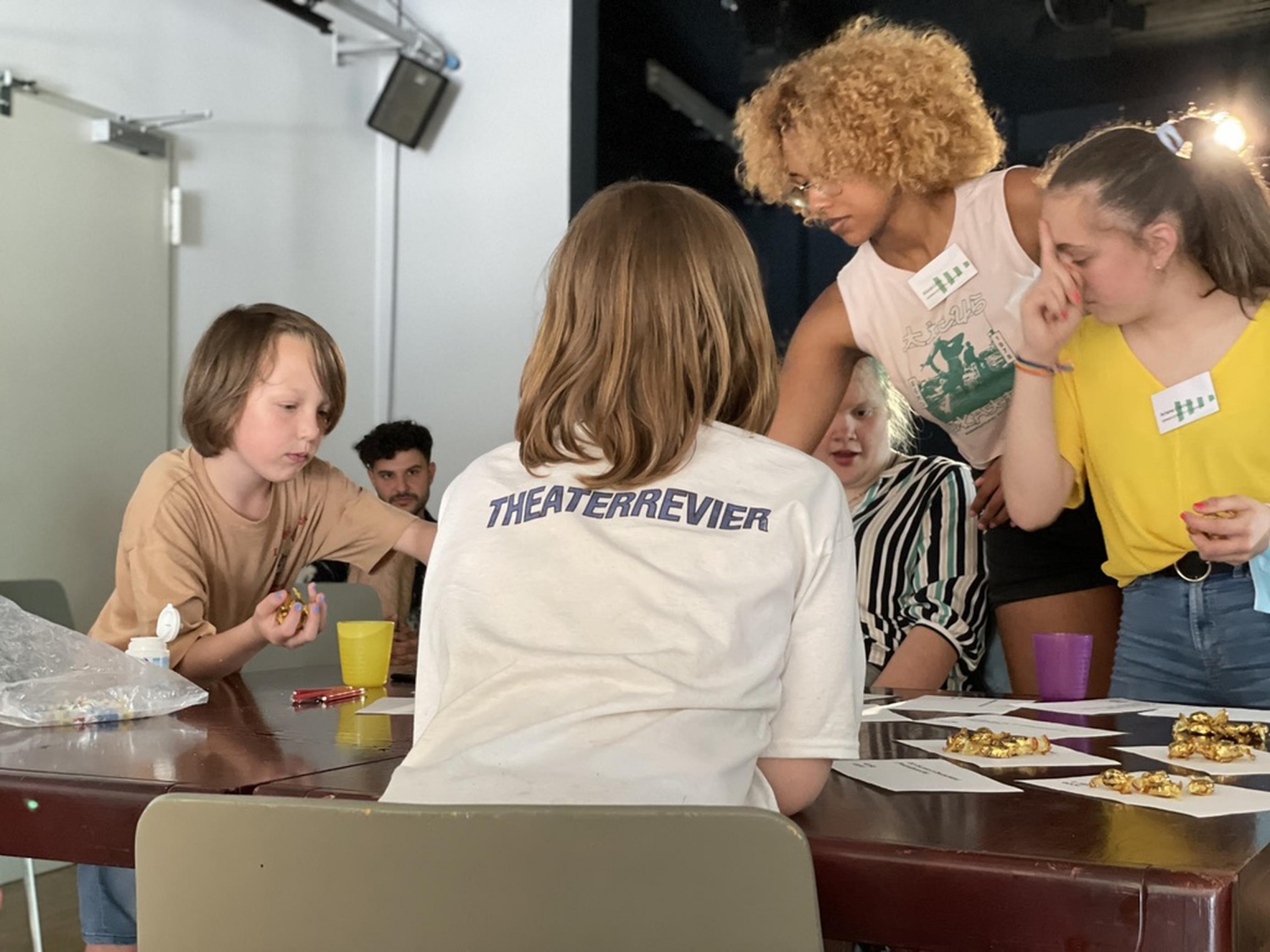 An einem Tisch verhandeln die fünf Kinder/Jugendliche, wofür das gewonnene Geld ausgegeben werden soll.