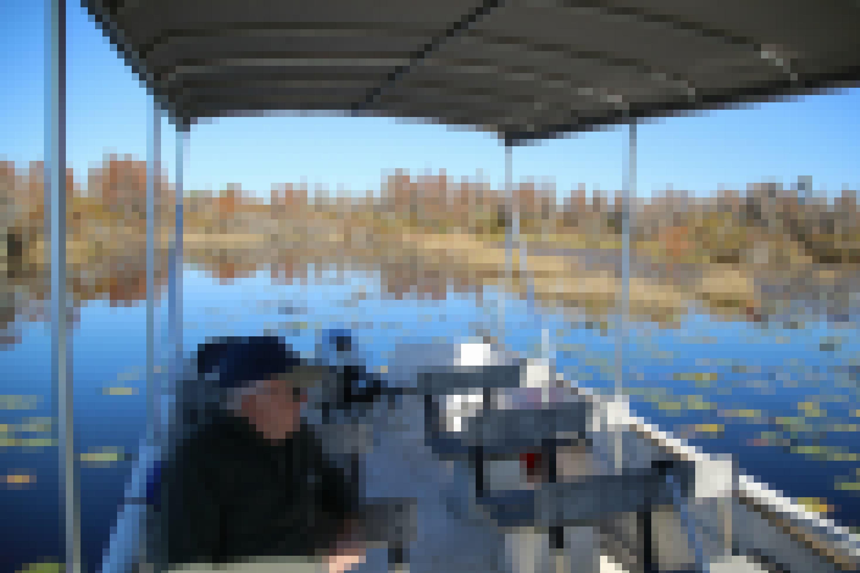 Ein Mann sitzt in einem Boot und betrachtet das Wasser um sich herum.