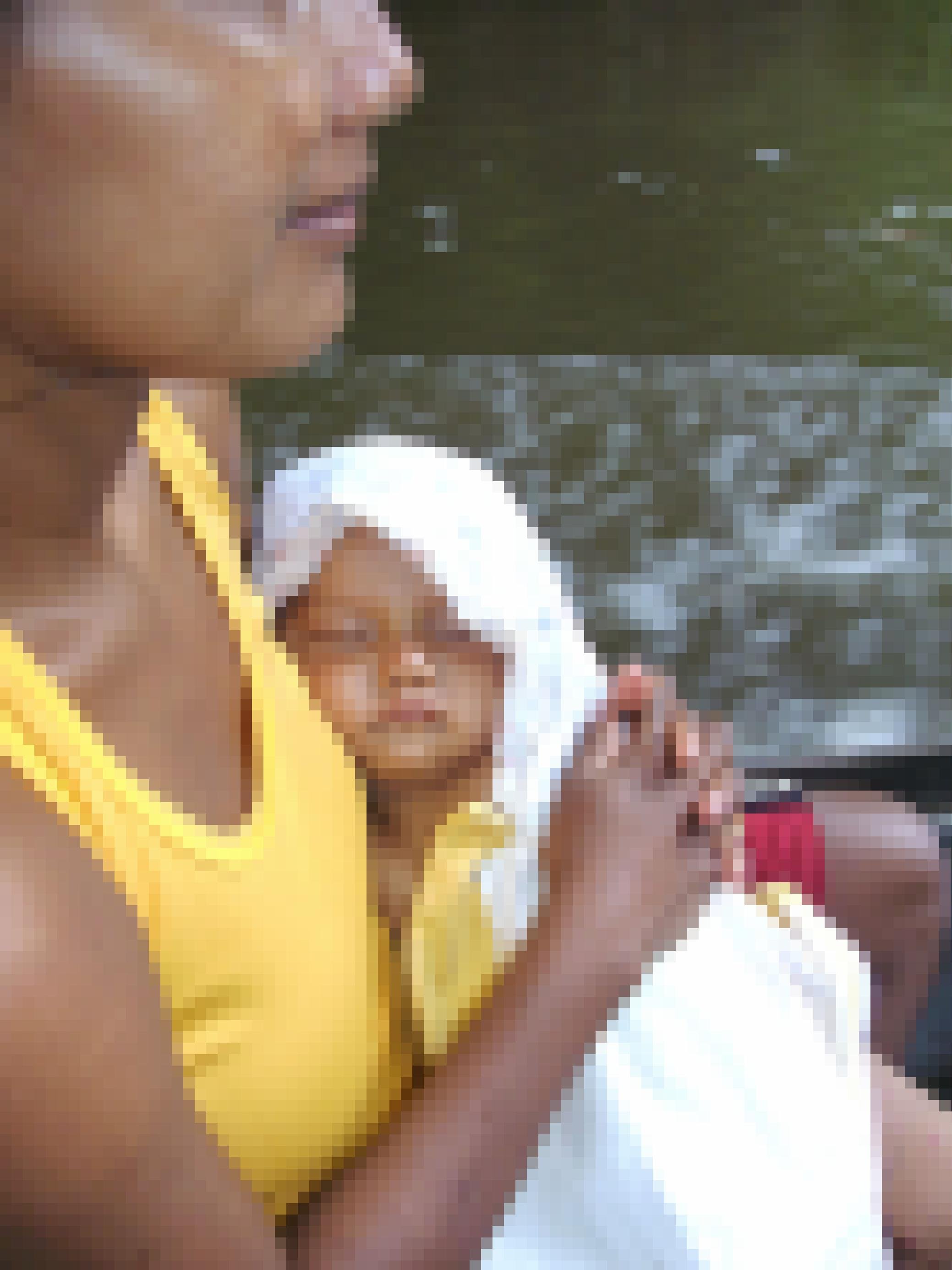 Eine indigene junge Frau presst ein schlafendes Kind an ihre Brust. Es ist in ein weißes Tuch eingewickelt. Sie fahren in einem Boot über den Fluss. Die Frau trägt ein Top und kurze Hosen.