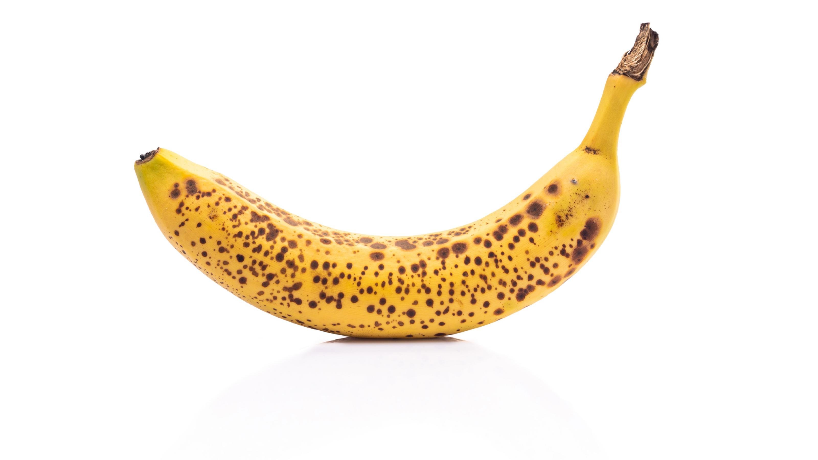 Halbnahe einer braun gefleckten Banane vor weißem Hintergrund.