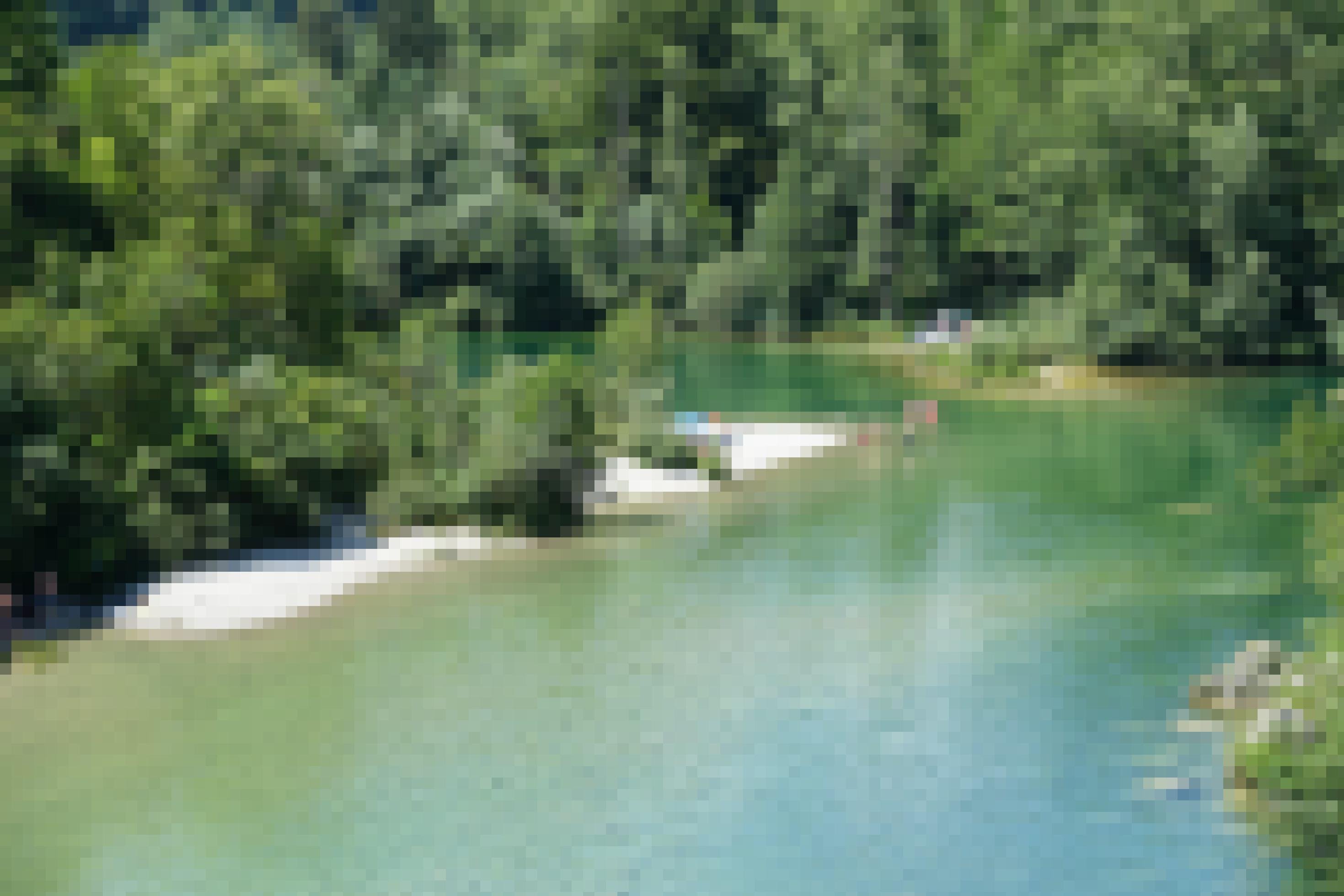 Kurve eines smaragdgrünen Flusses, rundum viel Wald, im Wasser und am Kiestrand Menschen in Badekleidung.