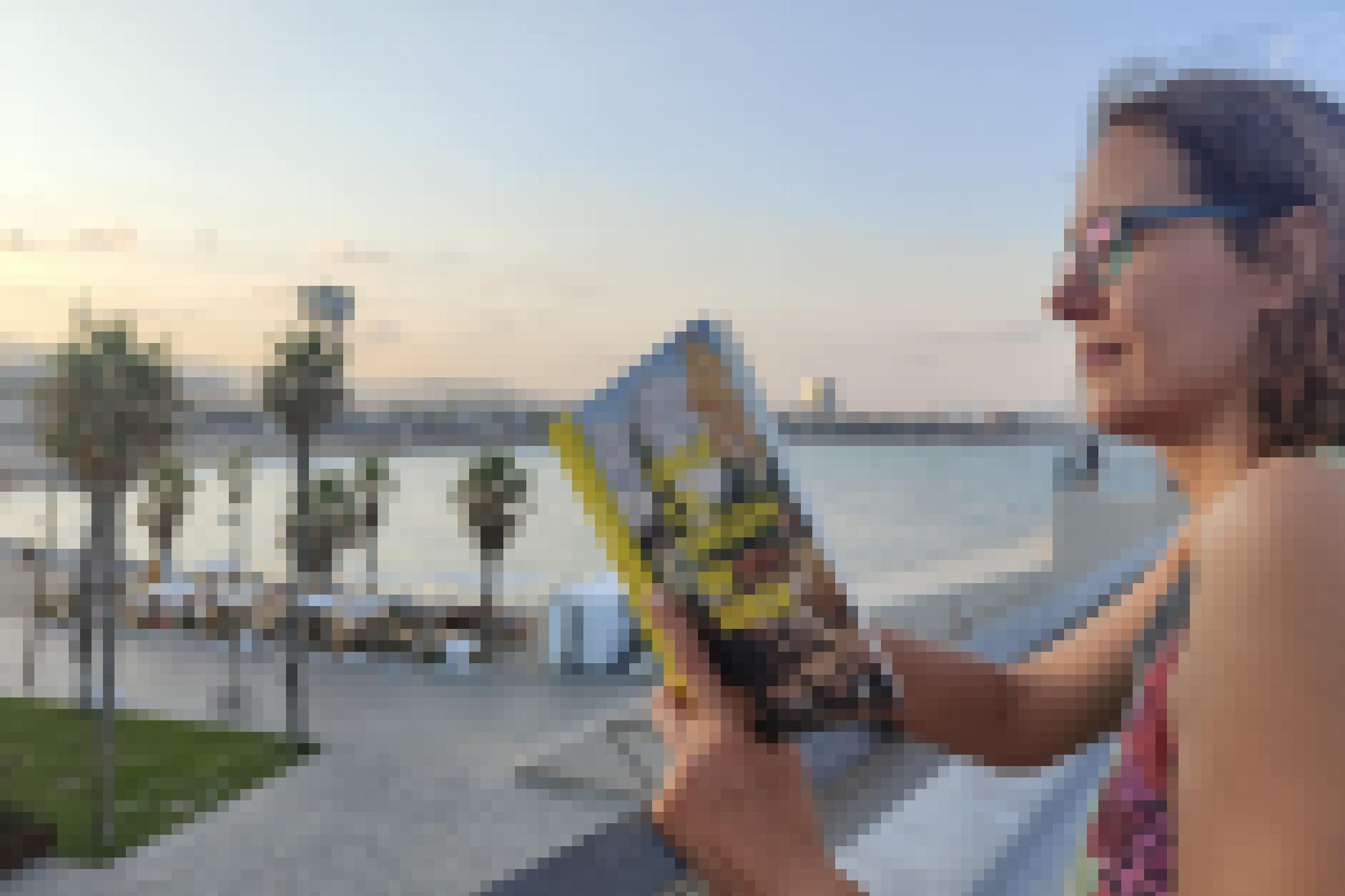 Julia Macher liest im Buch „Singe ich, tanzen die Berge“ von Irene Solà, im Hintergrund ist der Strand von Barcelona zu sehen.