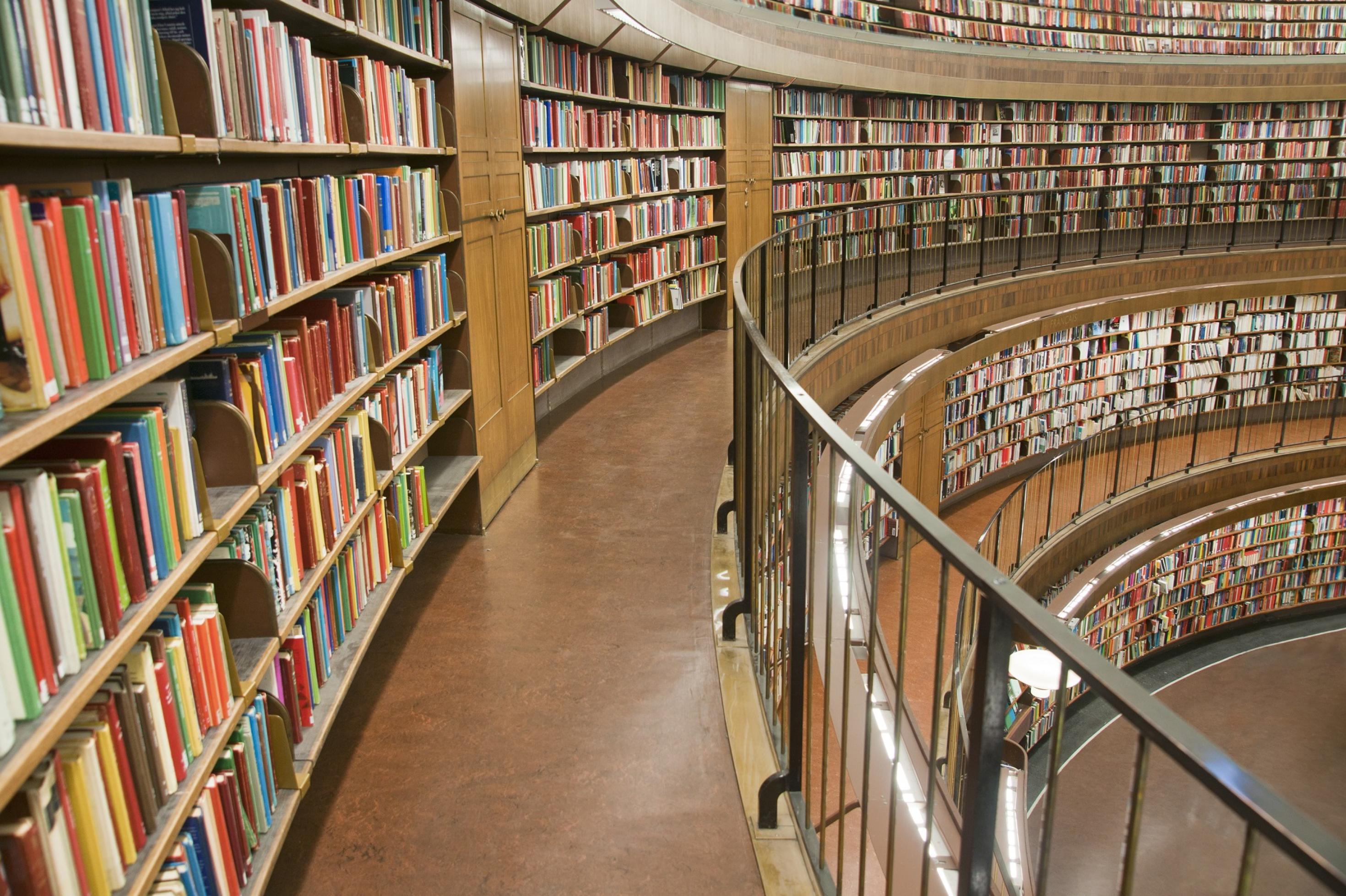 Eine Bücherei, die mehrstöckig aufgebaut ist, ein Gang geht zur Seite zur oberen rechten Ecke des Bildes