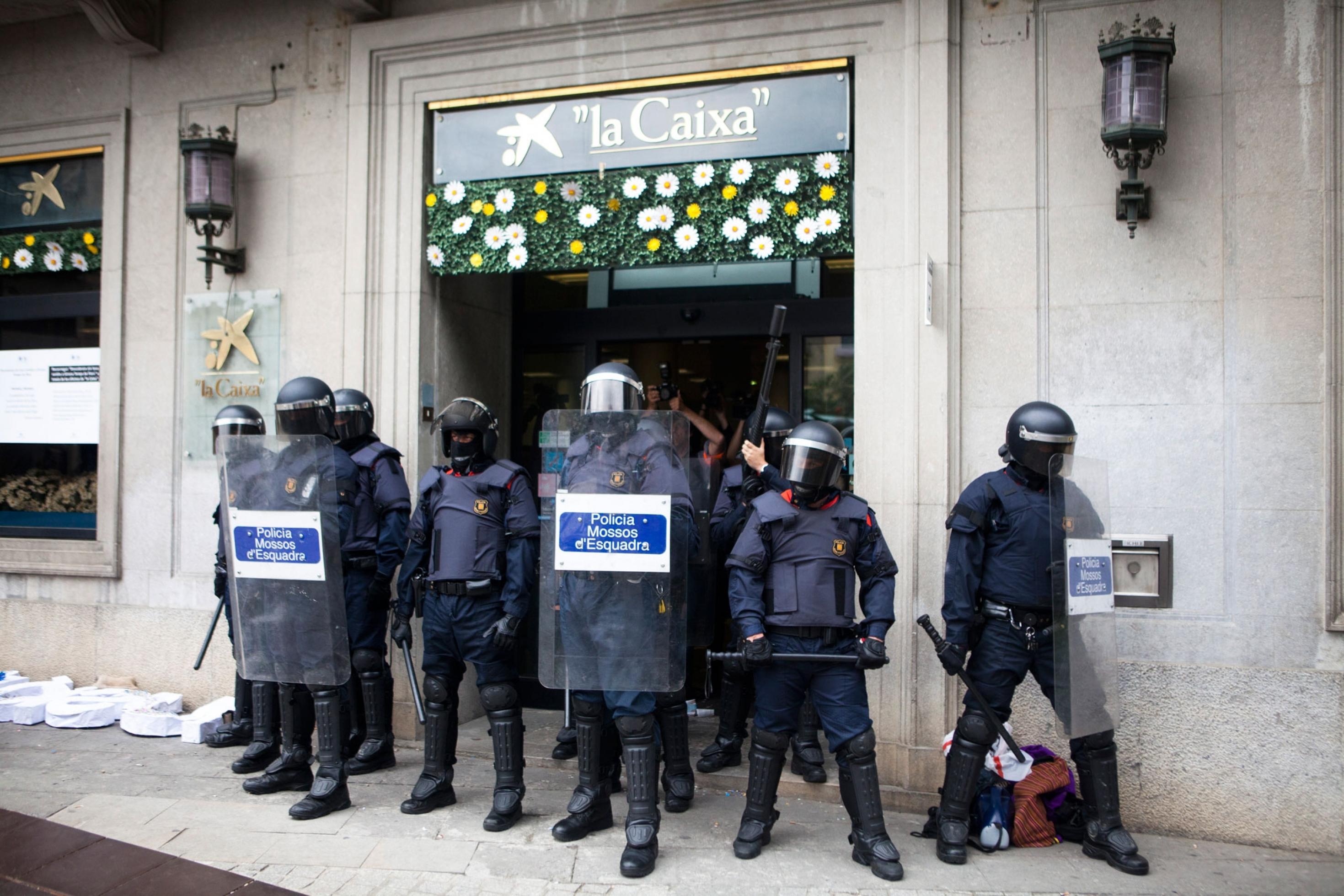 In Katalonien wird eine Bank von schwer bewaffneten Polizisten bewacht.