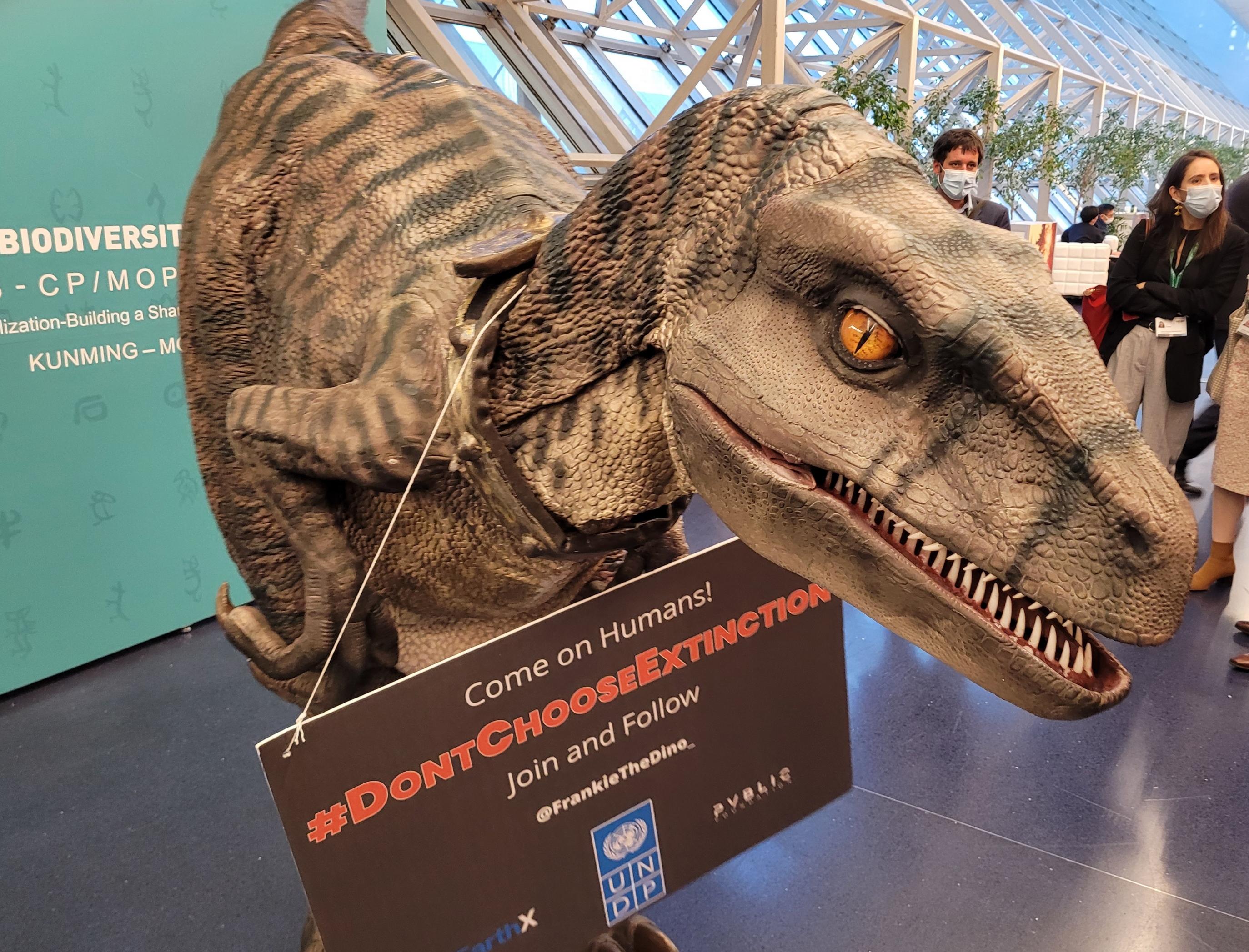 Gegen eine neue Aussterbewelle protestiert auf der COP15 ein Dinosaurier