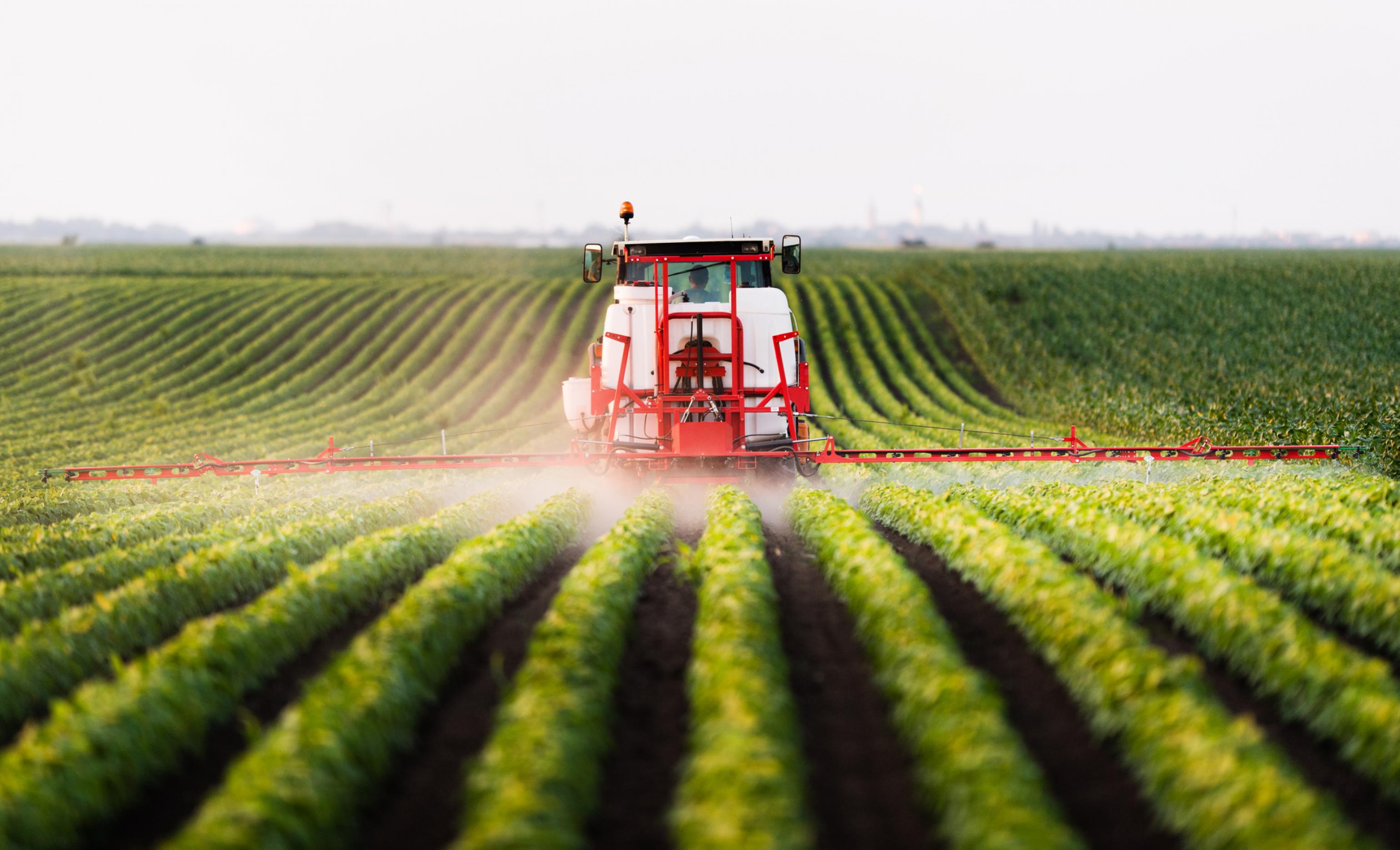 Ein Traktor spritzt Pestizide auf Sojabohnen