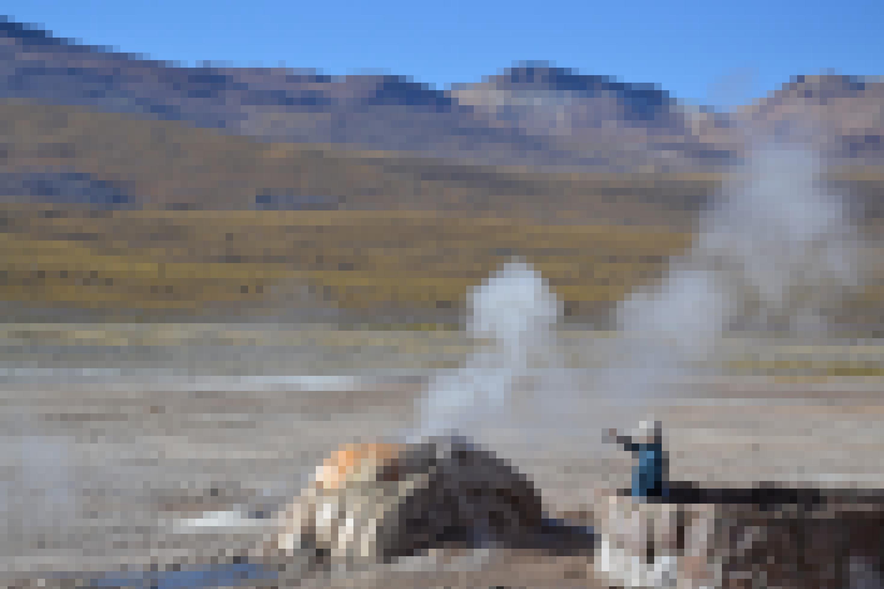 Tourist mit Handy vor dem rauchenden Geysir in El Tatio, Chile.