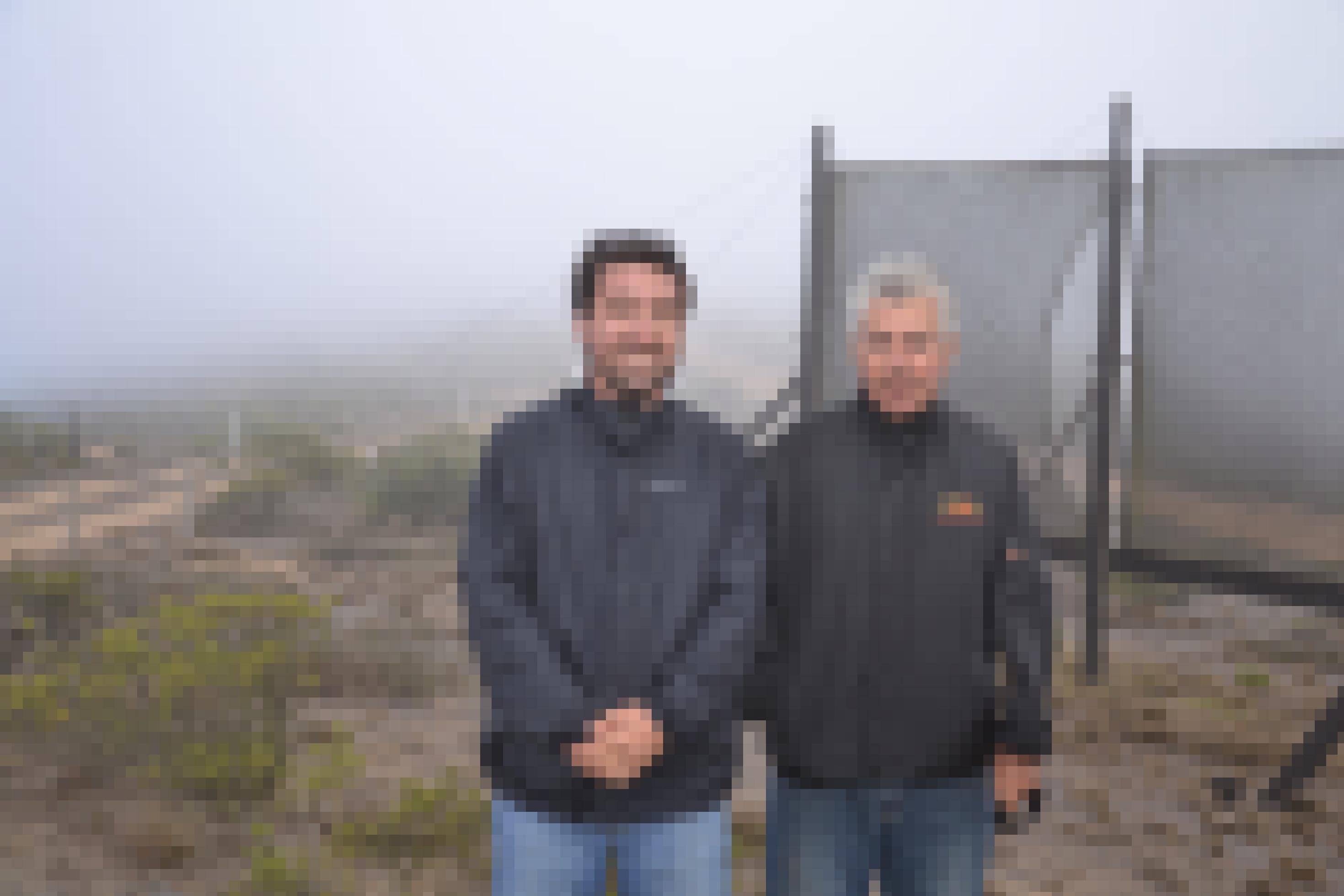 Zwei Männer vor einem aufgespannten Netz, das den Nebel kondensiert in Pena Blanca, Chile.