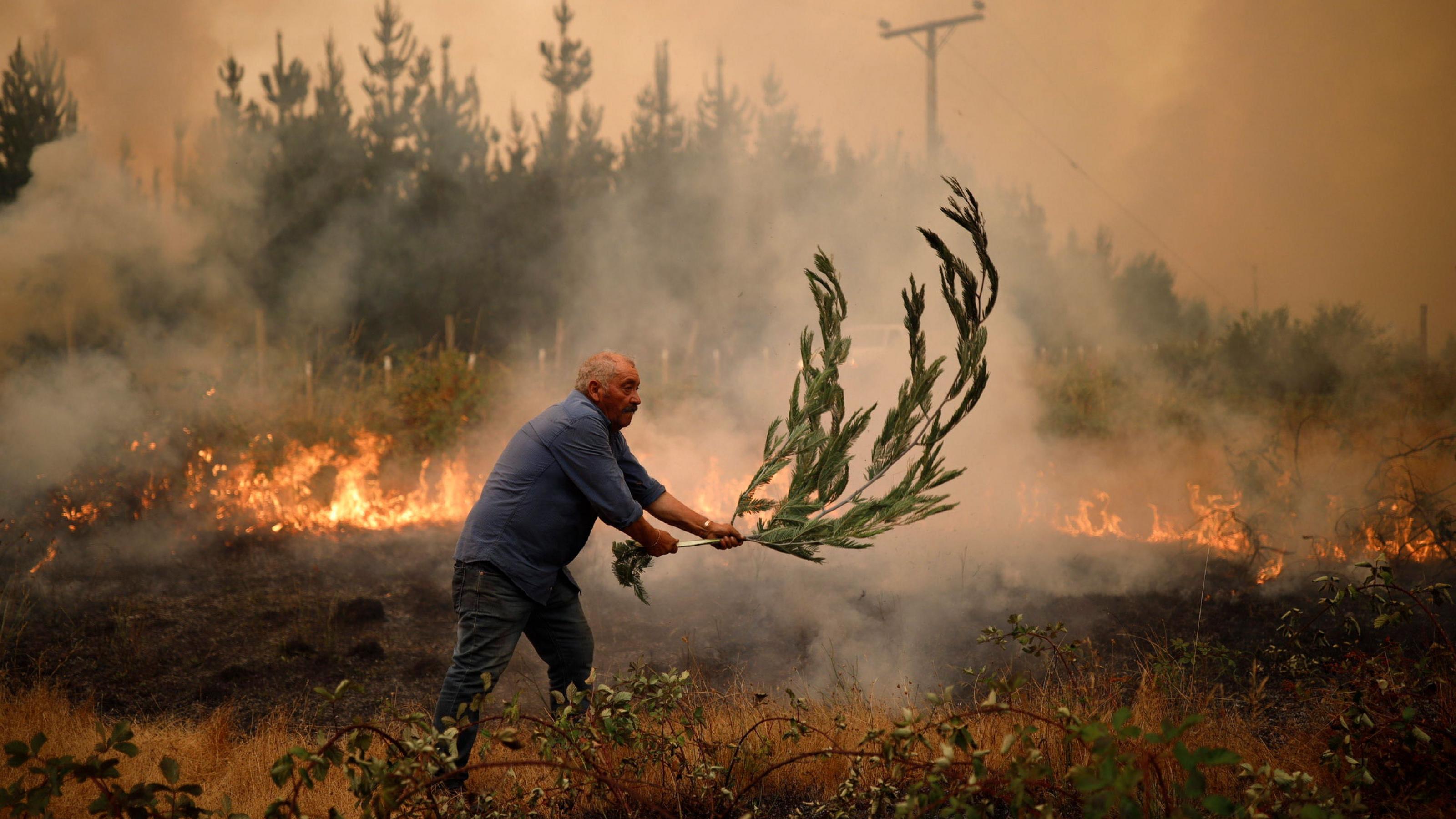 Ein Mann versucht ein starkes Feuer zu löschen. Seit Februar 2023 erschüttern verheerende Waldbrände Chile.