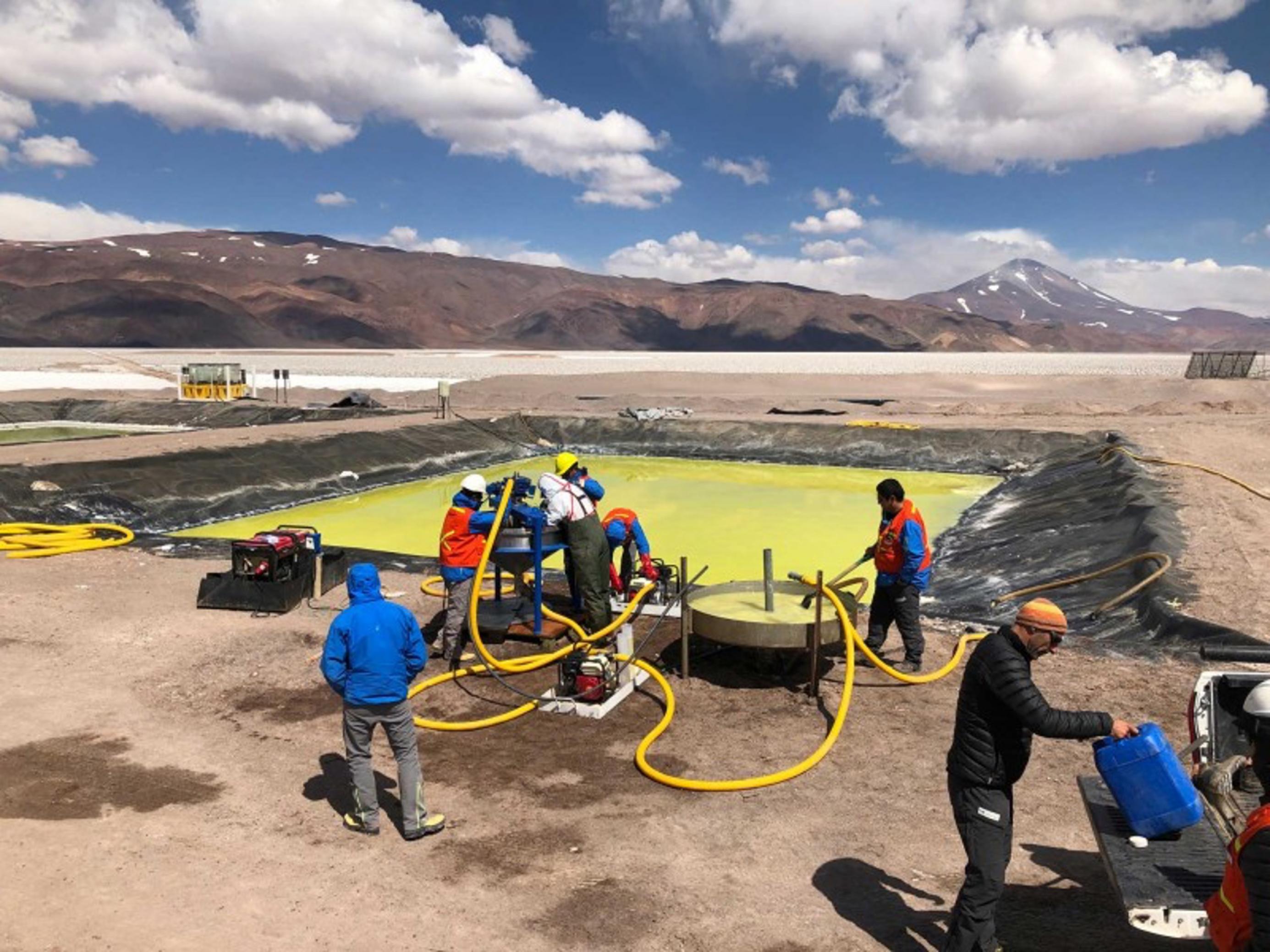 Arbeiter vor einem Becken mit gelber Flüssigkeit beim Lithium-Abbau