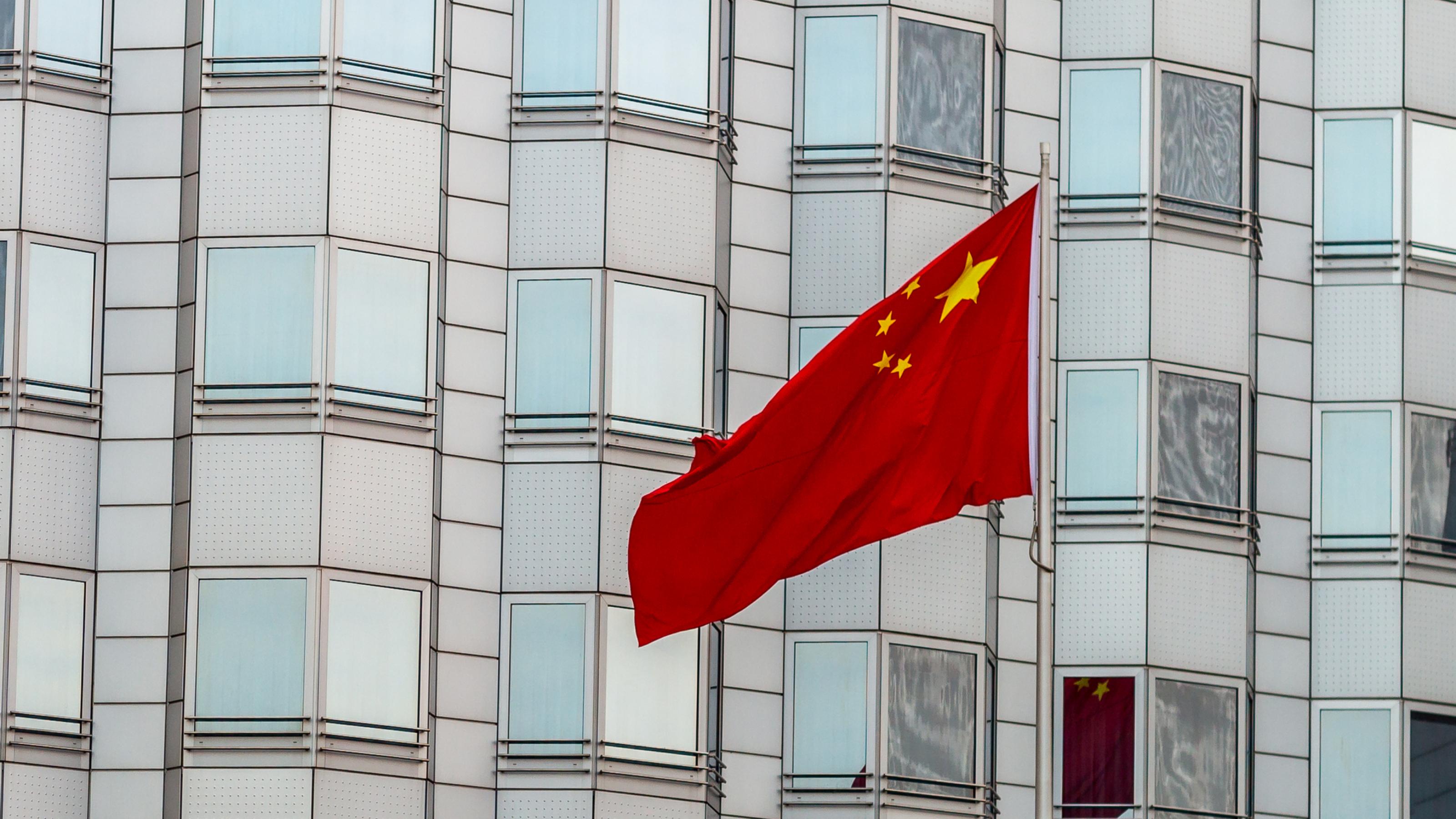 Das Bild zeigt die chinesische Botschaft in Berlin mit einer wehenden Flagge des Landes.