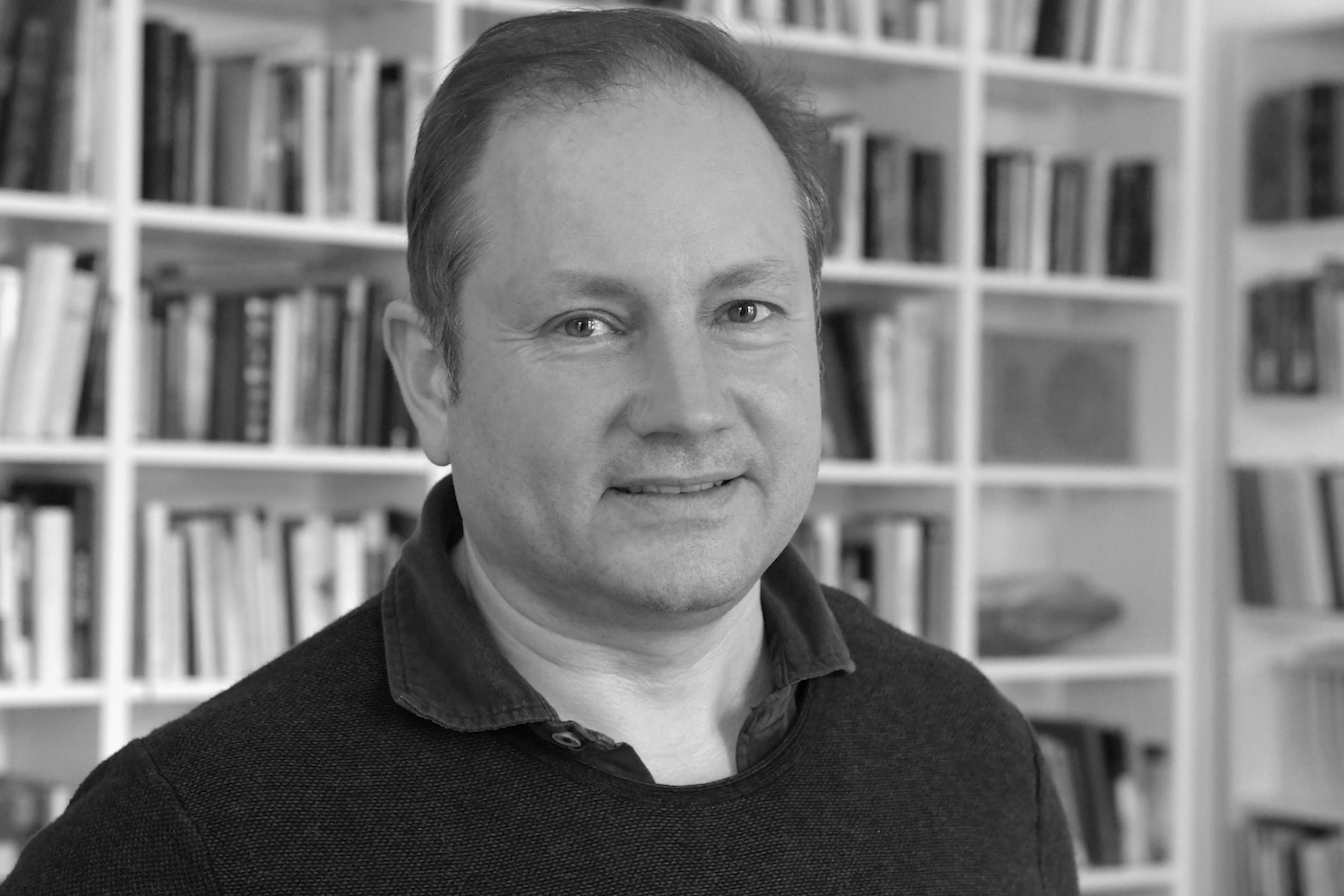 Portrait-Aufnahme von Christian Schwägerl vor einem Bücherregal in schwarz/weiß.