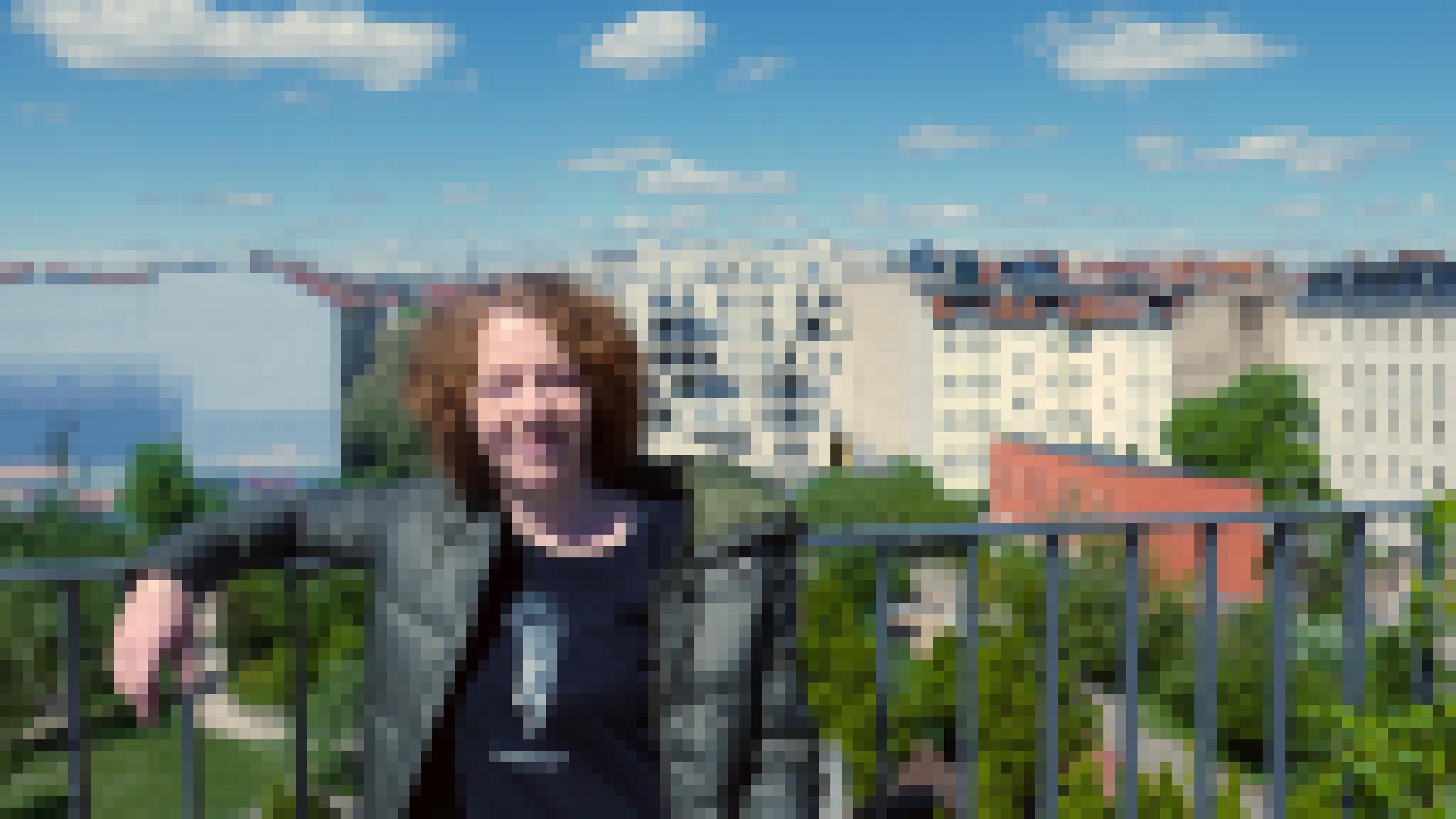 Christiane Habermalz lehnt an einem Geländer. Im Hintergrund sieht man einen Park und mehrstöckige Wohnhäuser.