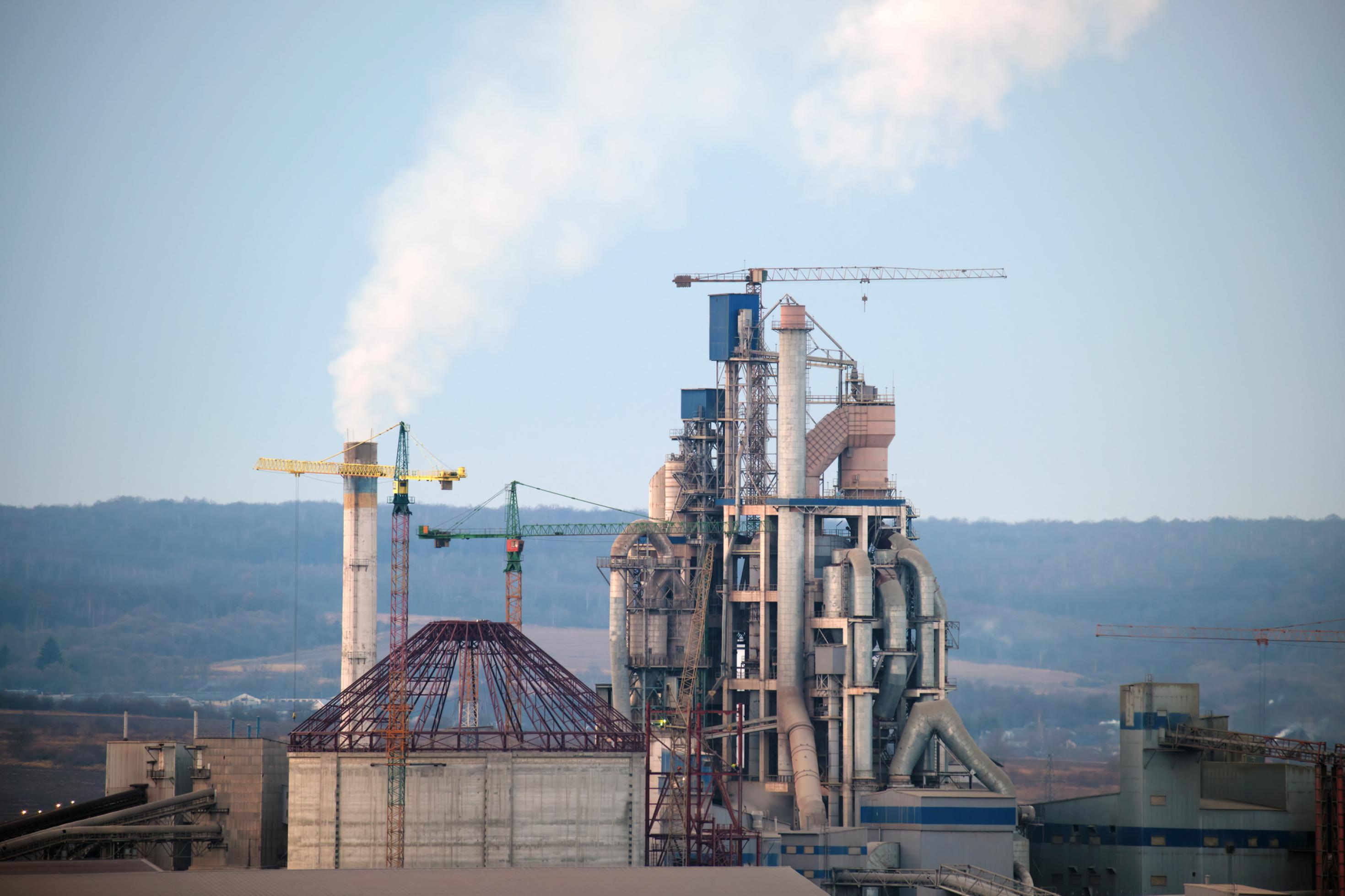 Ein Zementwerk mit Schornsteinen. Solche Fabriken stoßenviel Treibhausgas Kohlendioxid aus.