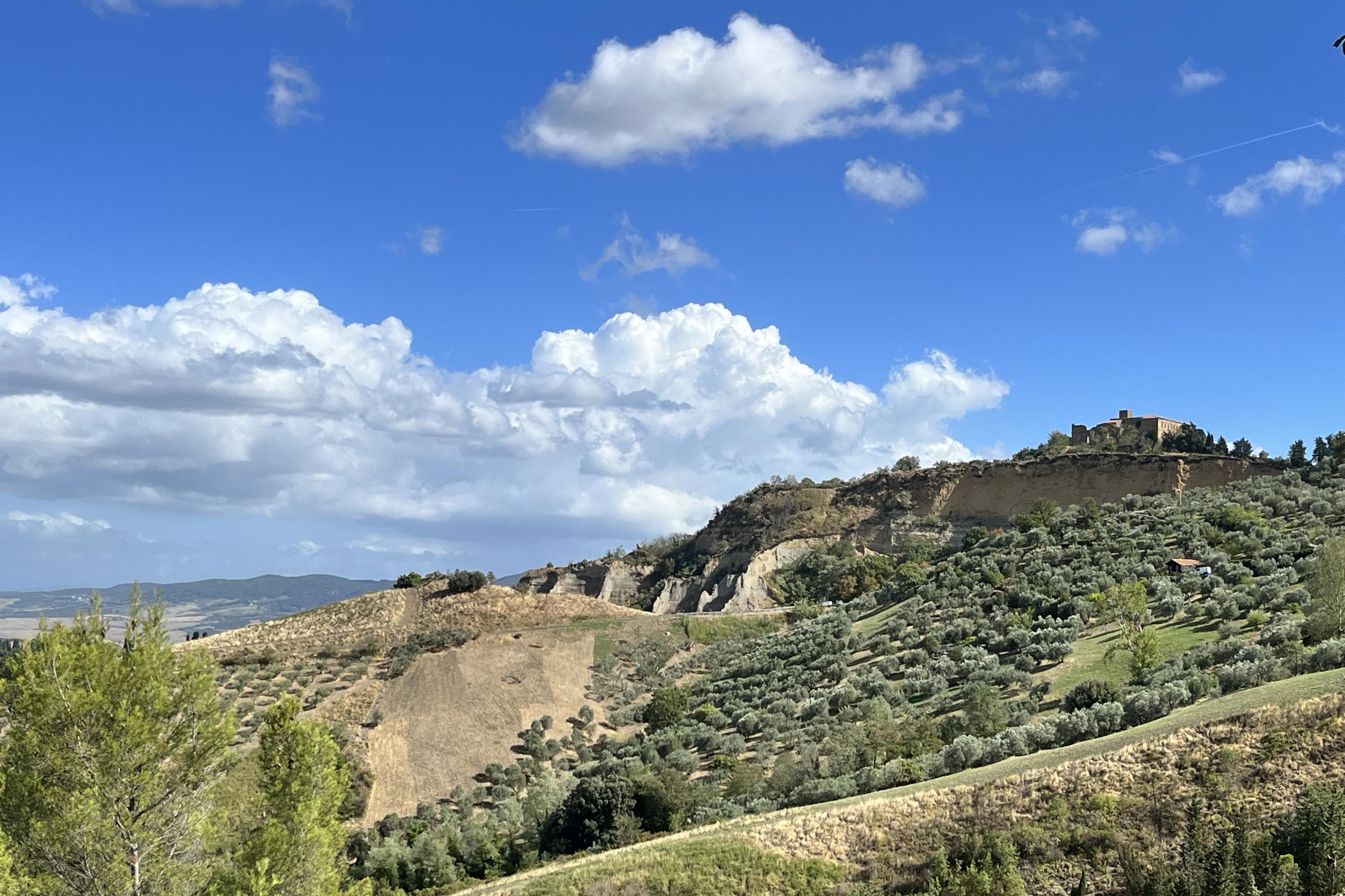 Block auf eine herbstliche Landschaft in der Toskana mit frisch gepflügten Feldern, Olivenhainen und einem alten Kloster