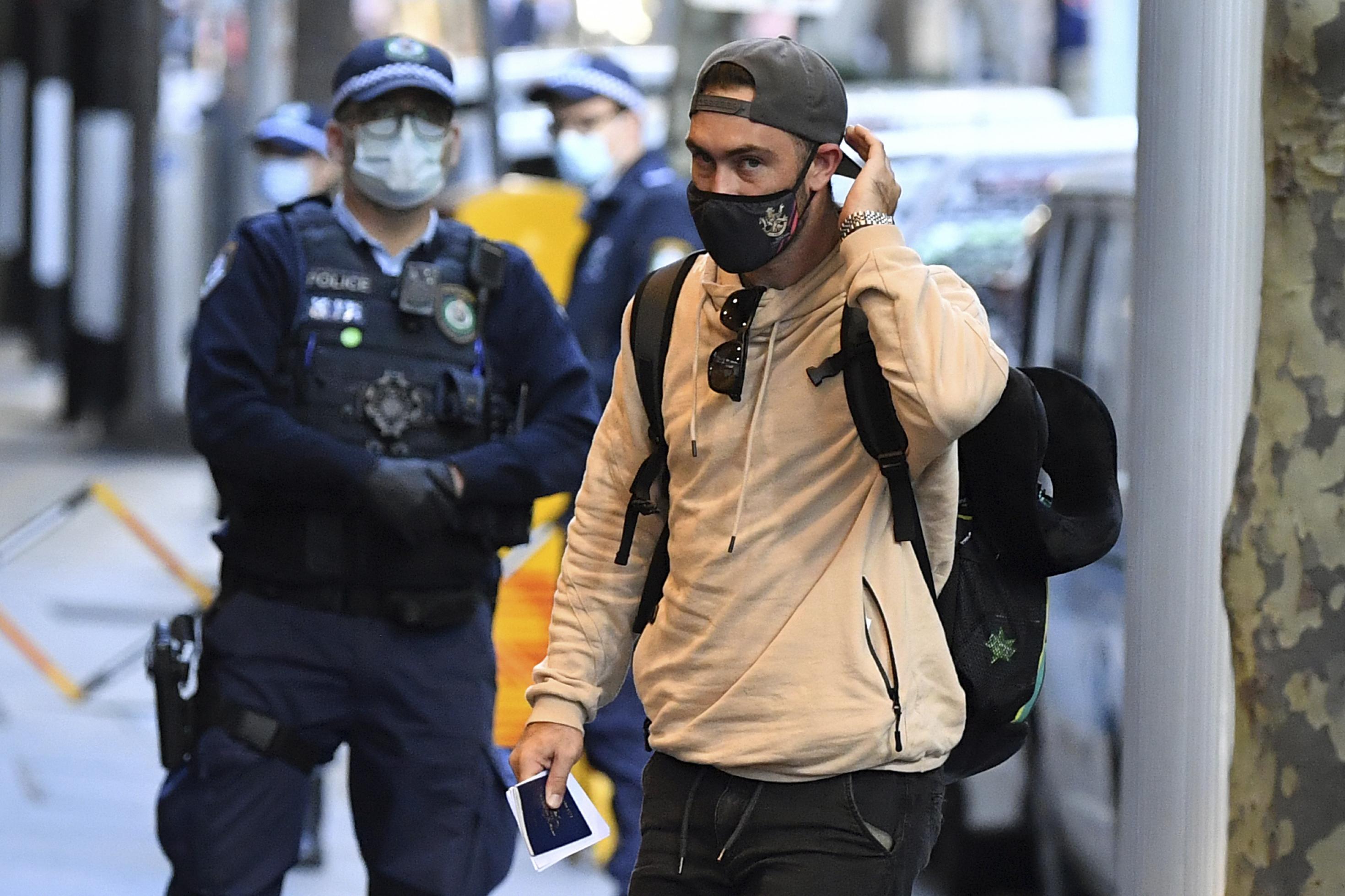 Der Sportler auf dem Bürgersteig, hinter ihm ein Polizist mit Gesichtsschutz.