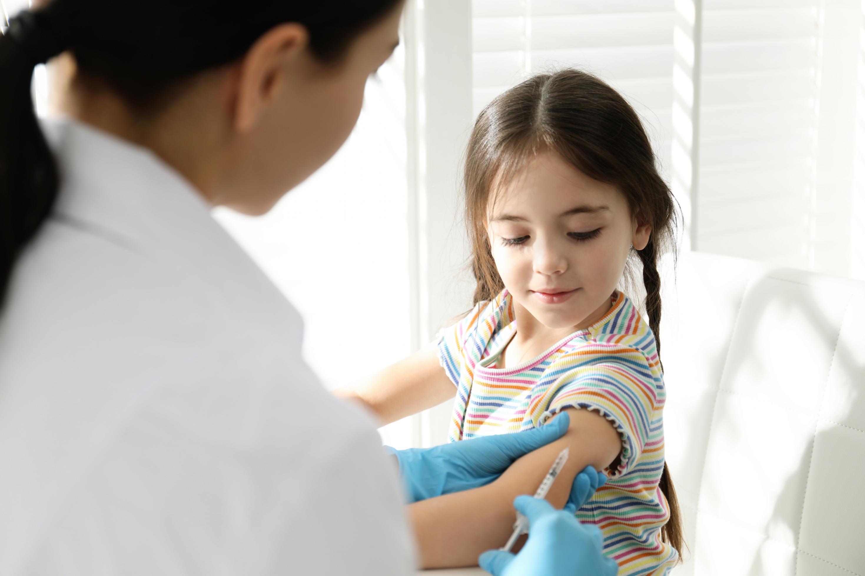 Ein kleines Mädchen erhält eine Impfung in den Oberarm.