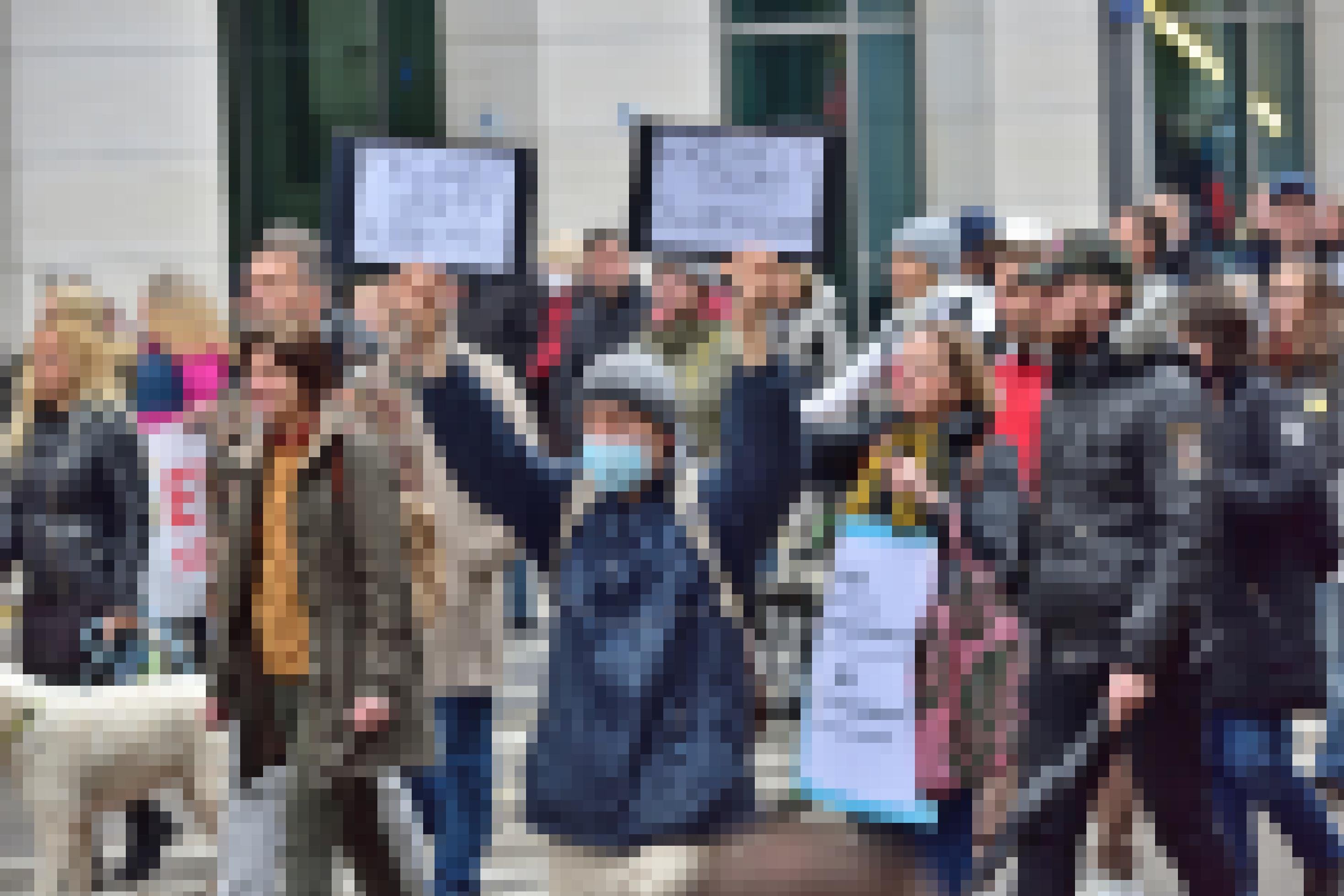 In einer Menschenmenge hält ein Mann zwei Schilder hoch: „Freiheit statt Biontech“ und „Freiheit statt Pharmalobby“