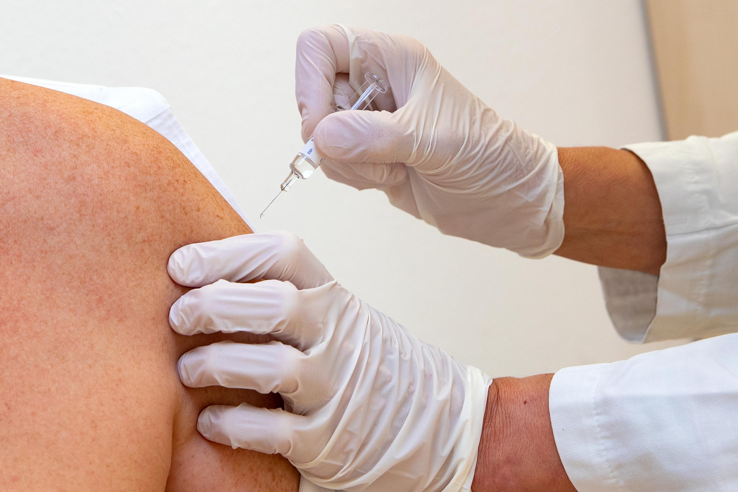 Eine Person von der nur die Schulter und der Oberarm zu sehen sind, bekommt mit einer kleinen Impfspritze einen Impfstoff injiziert.