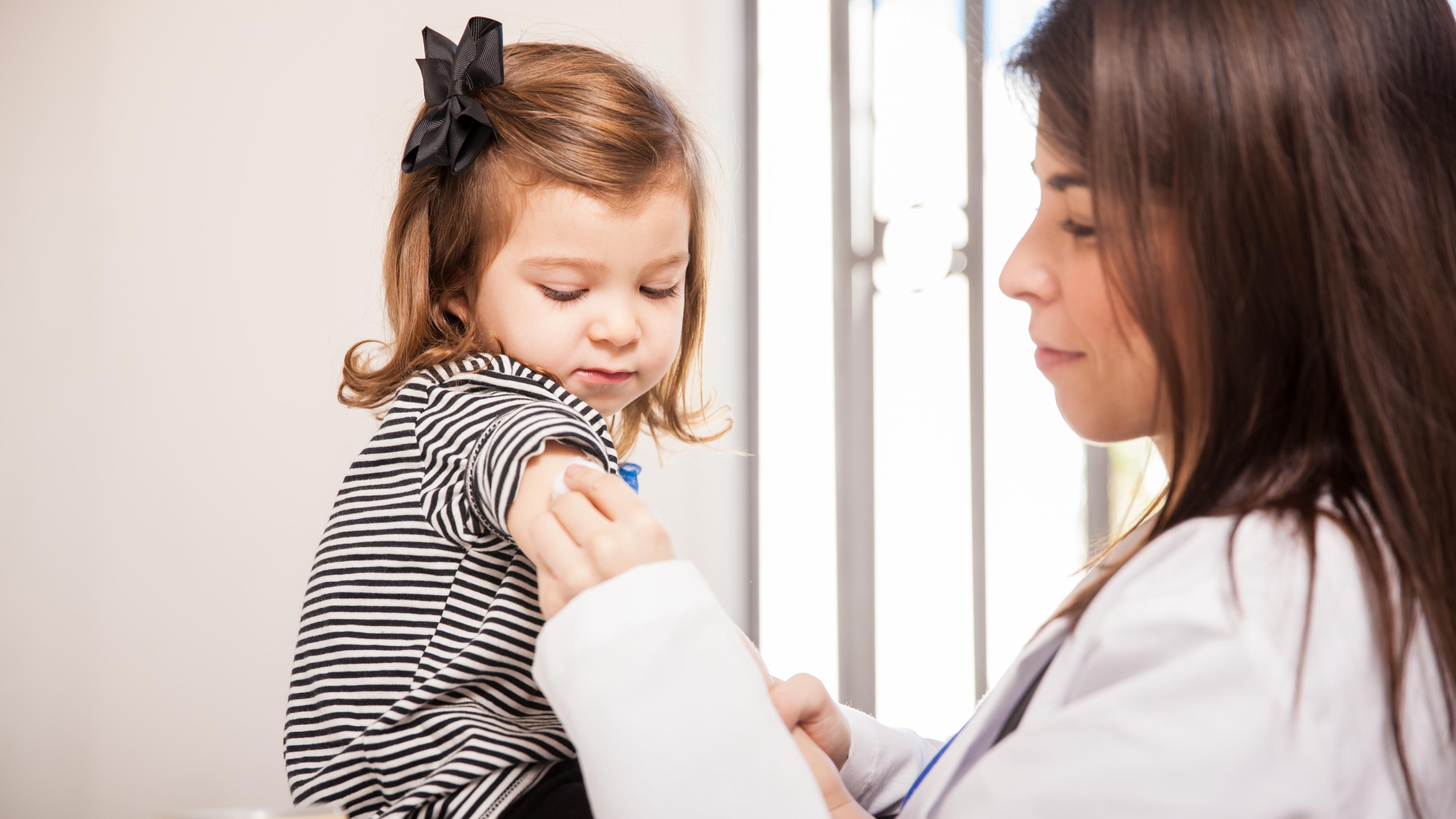 Eine Ärztin bereitet bei einem Kleinkind die Corona-Impfung vor.