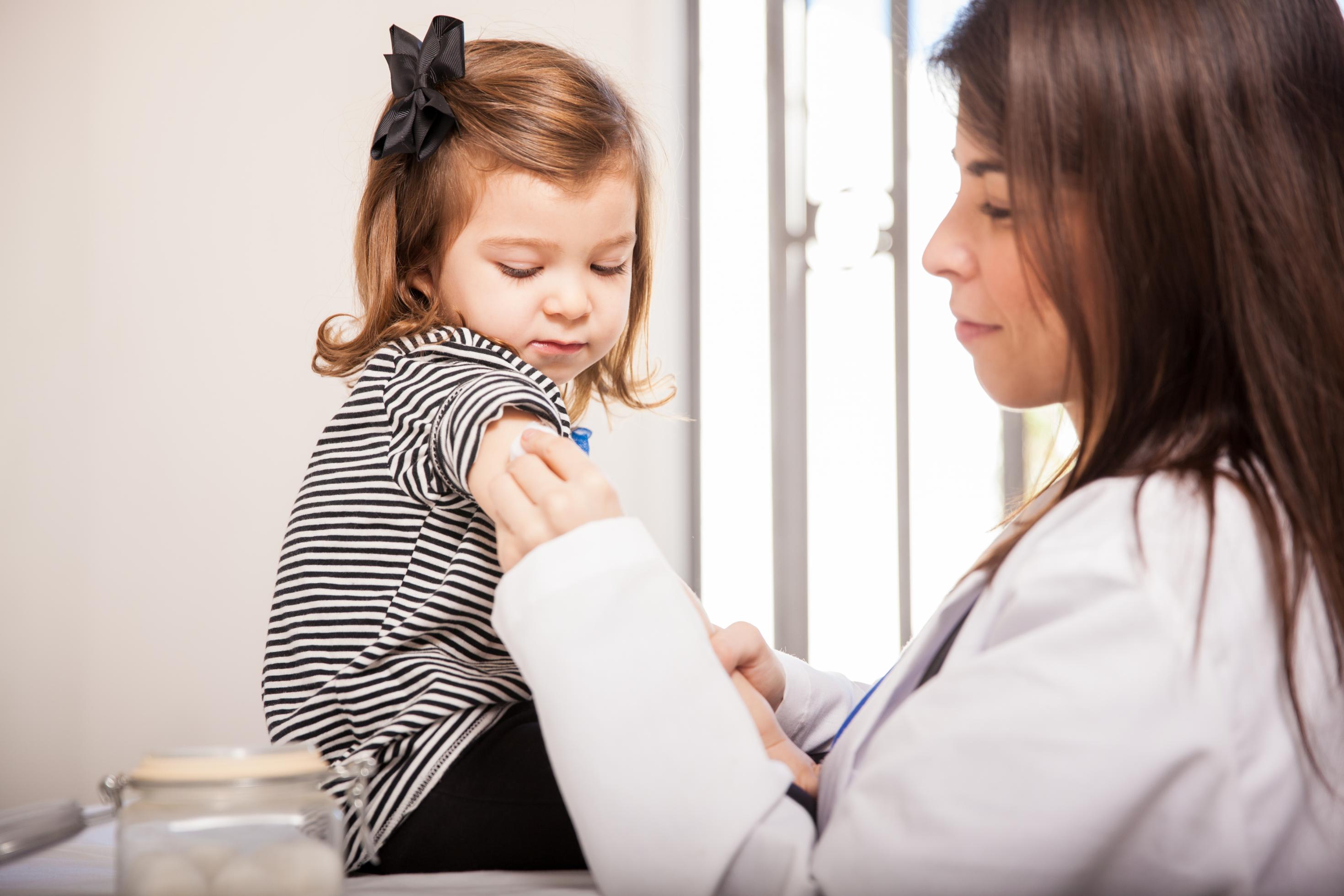 Eine Ärztin bereitet bei einem Kleinkind die Corona-Impfung vor.