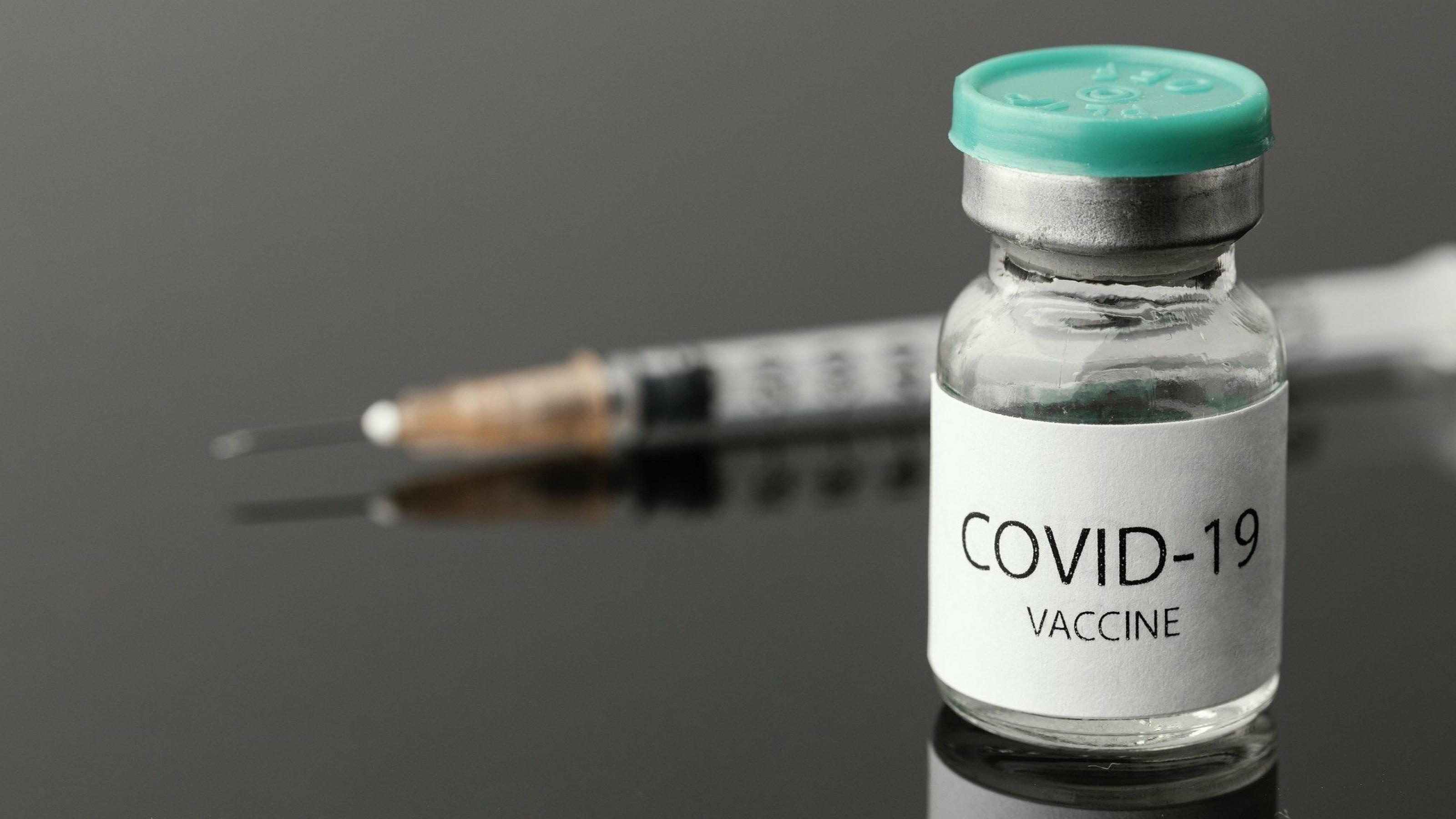 Ein Fläschchen mit Corona-Impfstoff, dahinter liegt eine Impfspritze bereit.