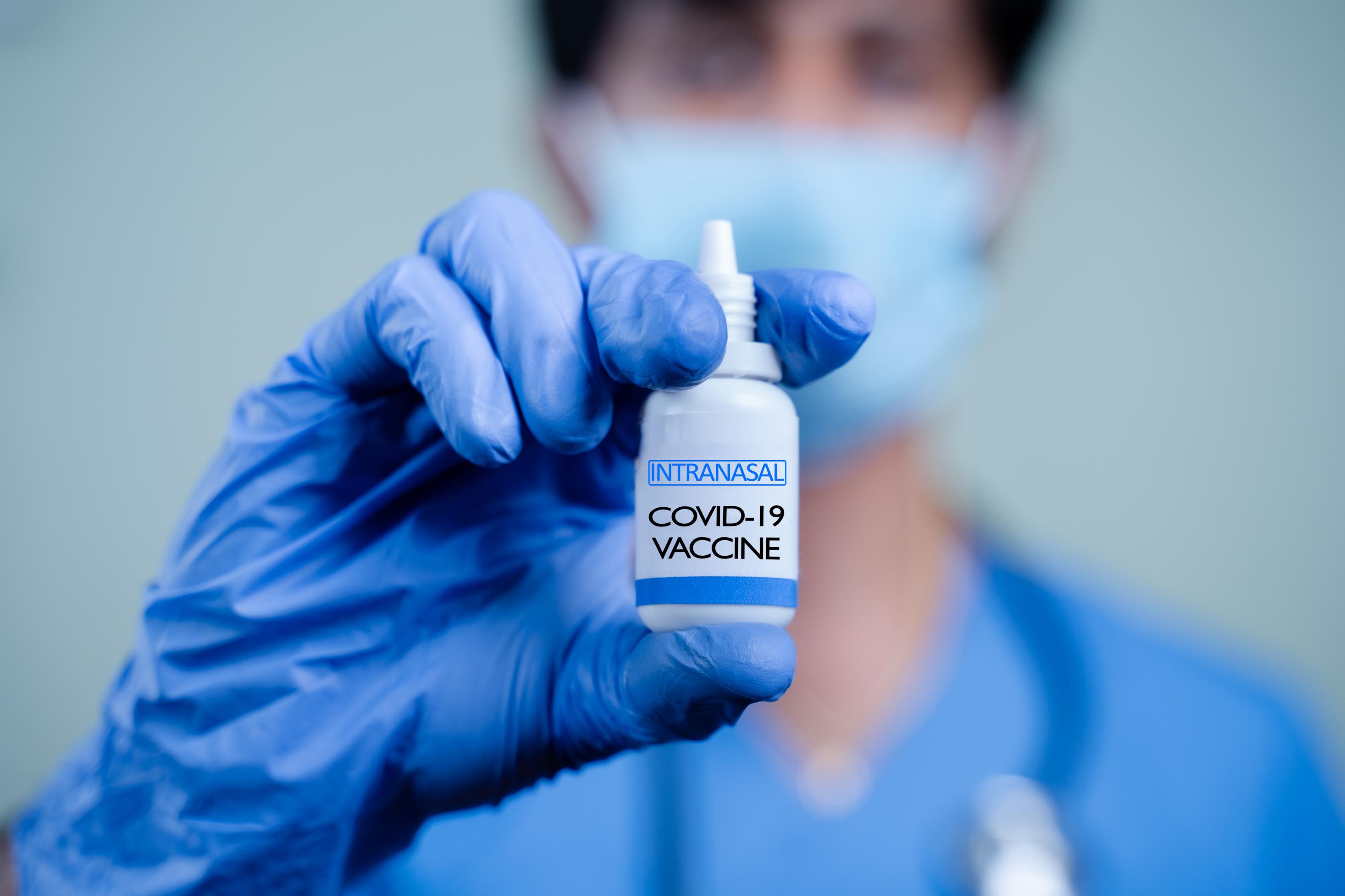 Eine Labormitarbeiter oder eine Labormitarbeiterin hält ein kleines Fläschchen in der Hand, in dem sich ein intranasaler Impfstoff gegen Covid-19 befindet.