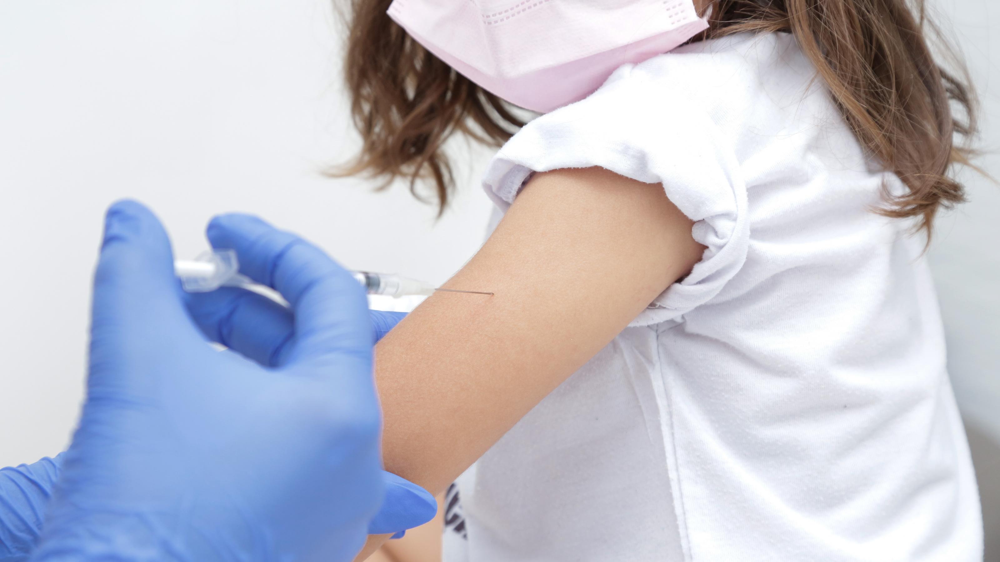Ein Mädchen in weißem T-Shirt wird gegen Covid-19 geimpft.